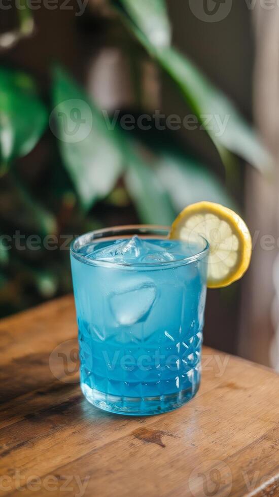 Blue cocktail with lemon slice on top of a wooden table photo