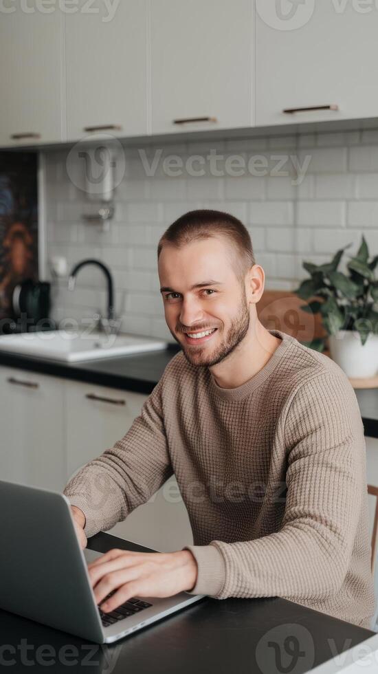 A man is sitting at a table with a laptop photo