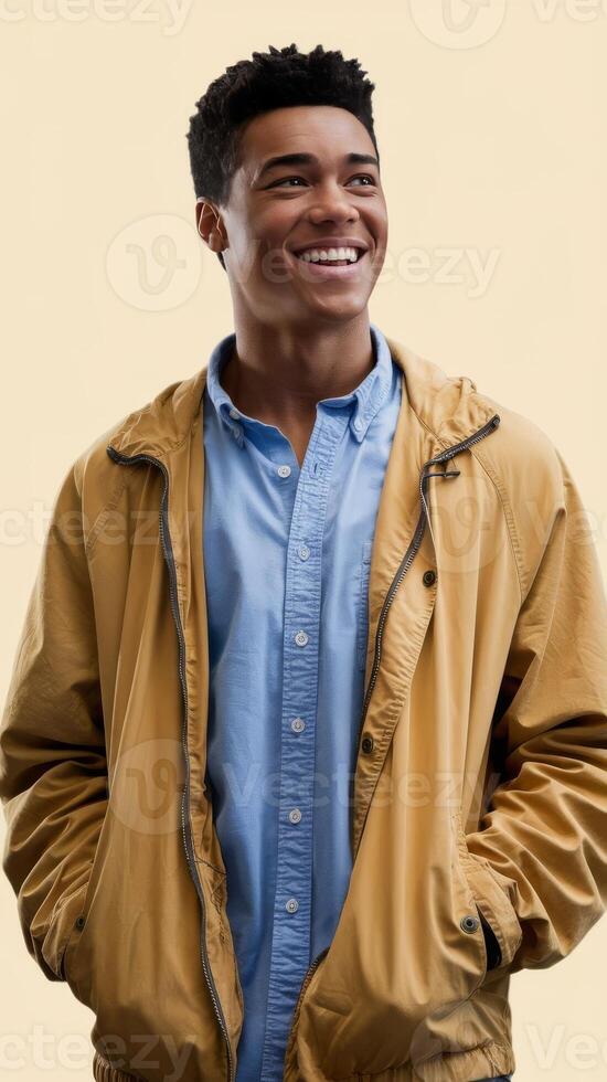 A young man is smiling in a tan jacket photo
