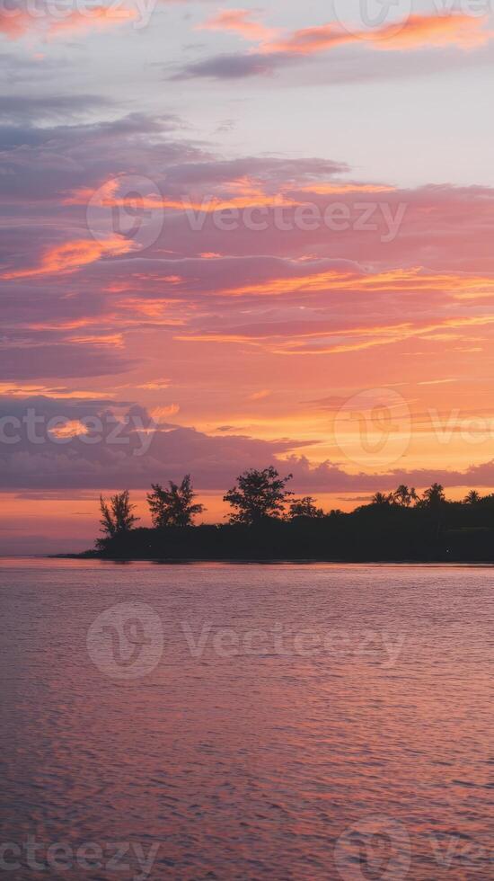 A sunset over the ocean with a small island in the distance photo
