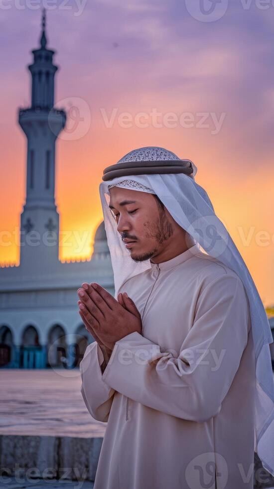 Prayer muslim man praying in front of the mosque at sunset photo