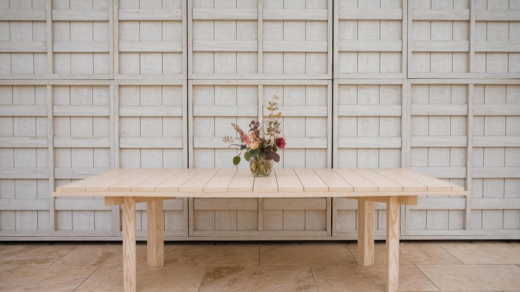 A table with flowers on it sitting in front of a white wall photo