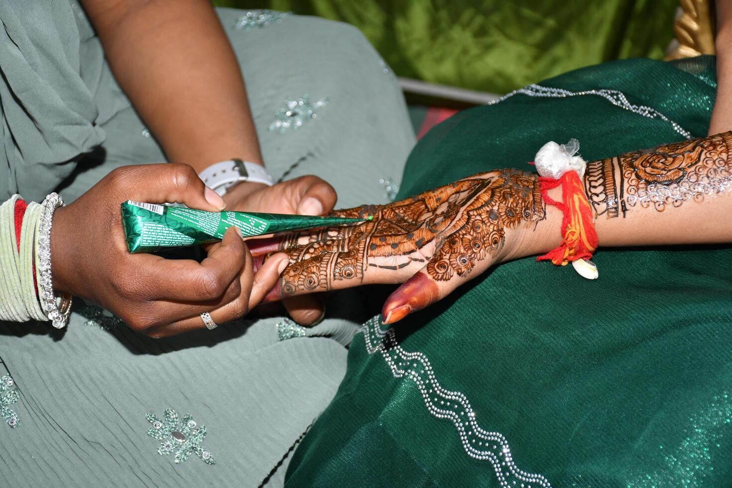 A woman getting her henna done by another woman photo