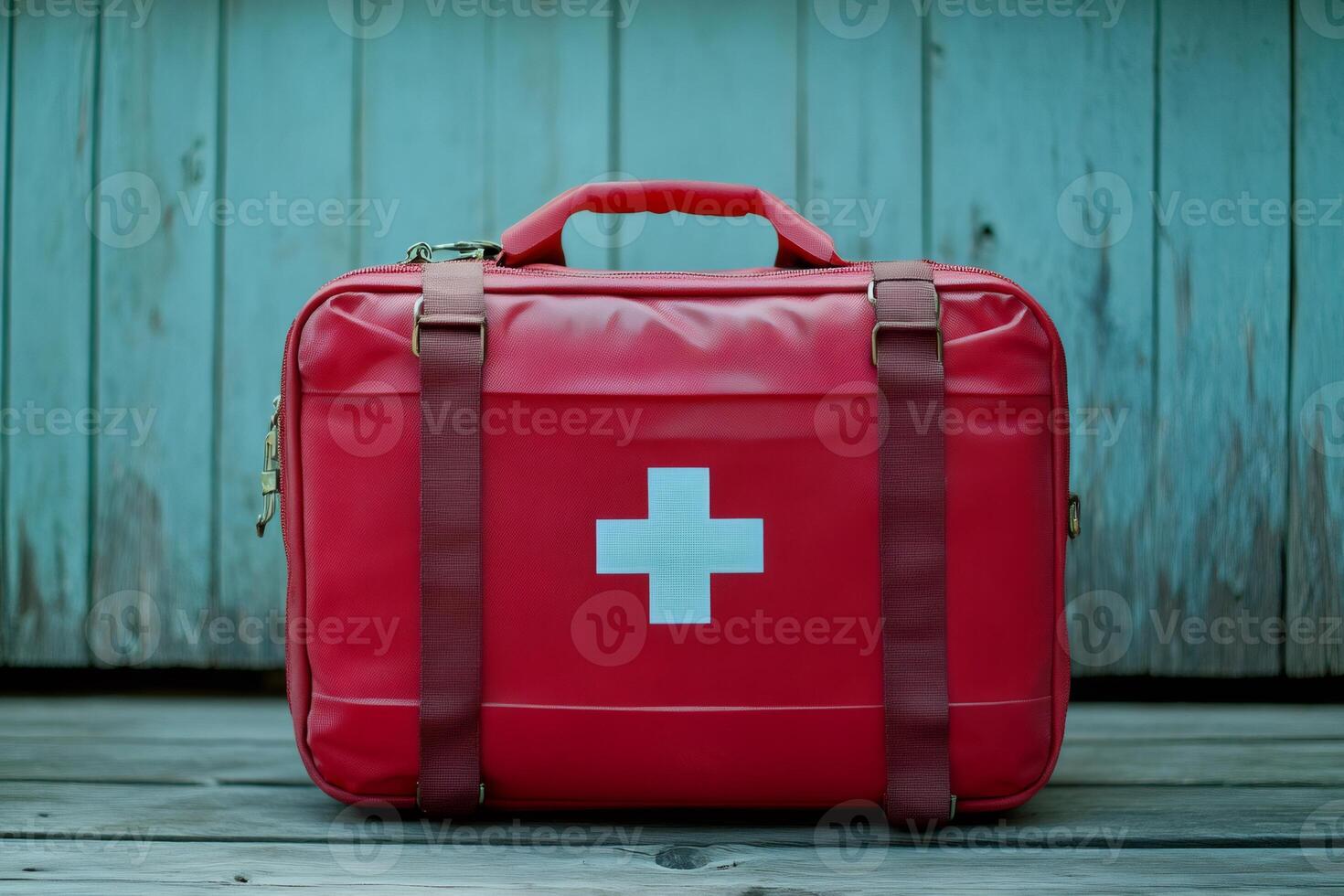 Red first aid kit bag sitting on wooden floor with turquoise background photo