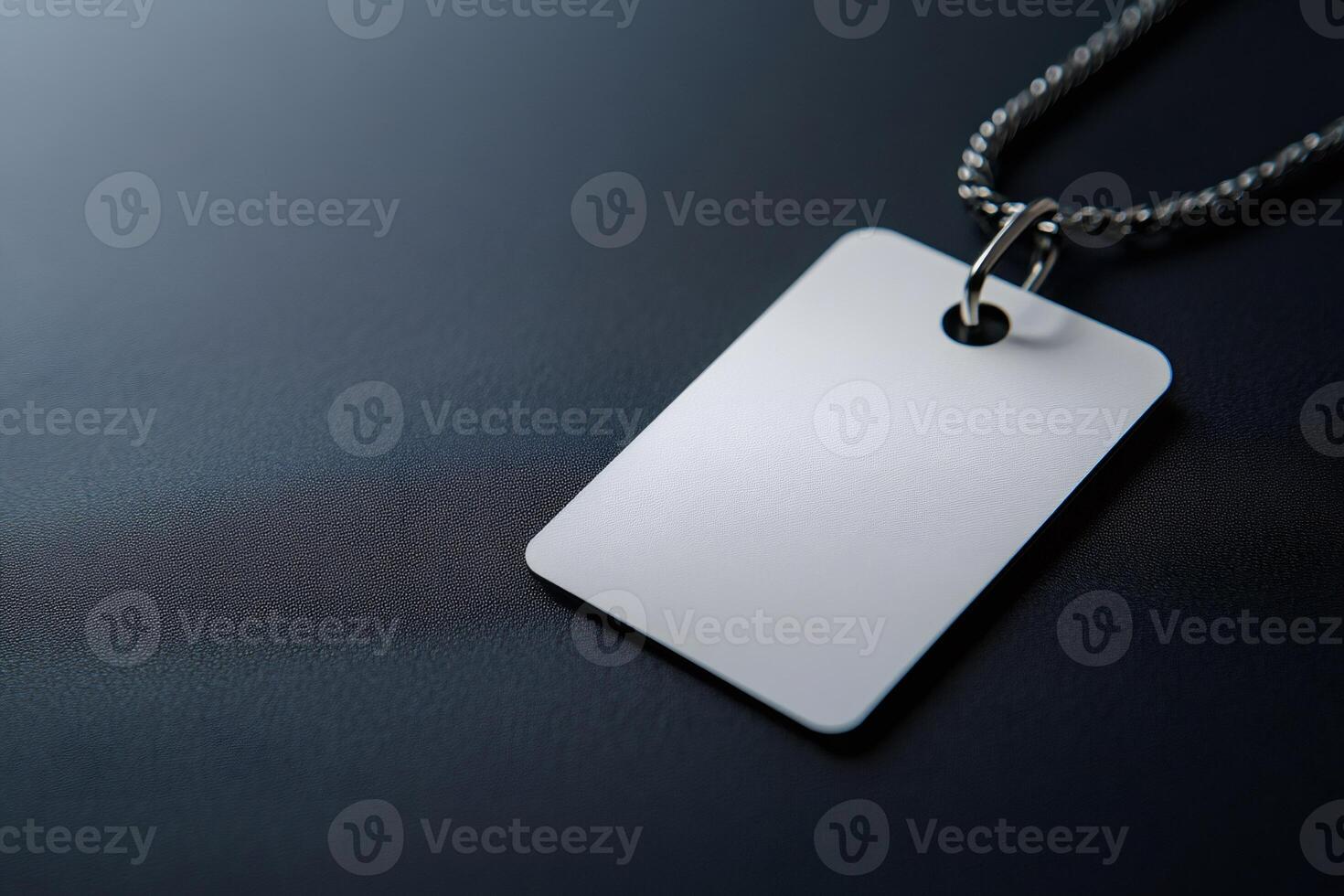 Blank white rectangular tag hanging from silver chain on dark background photo