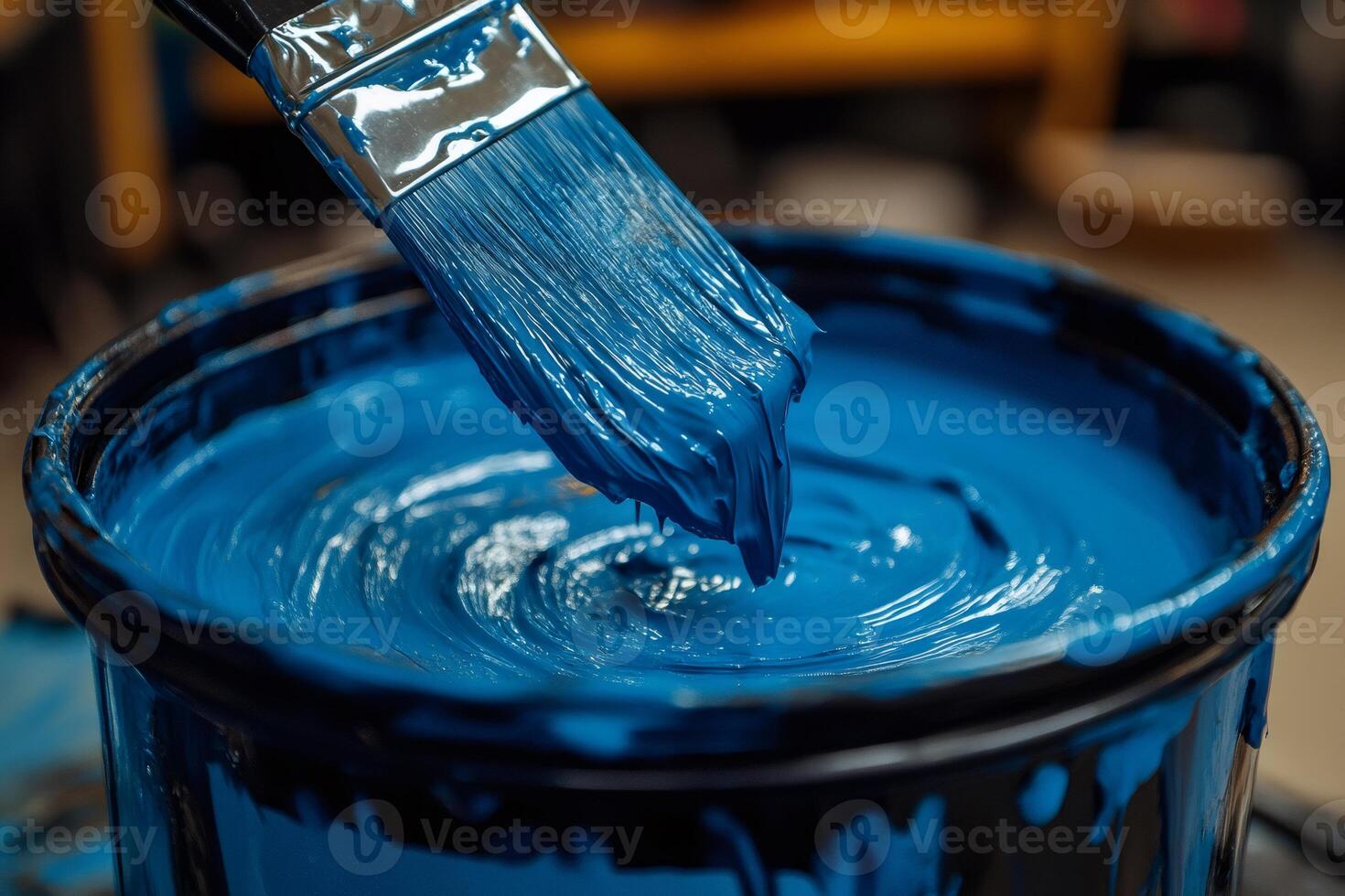 Paintbrush dripping deep blue paint into a can, ready for home renovation project photo