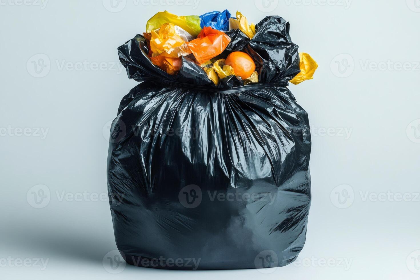 Black plastic trash bag overflowing with garbage on white background photo