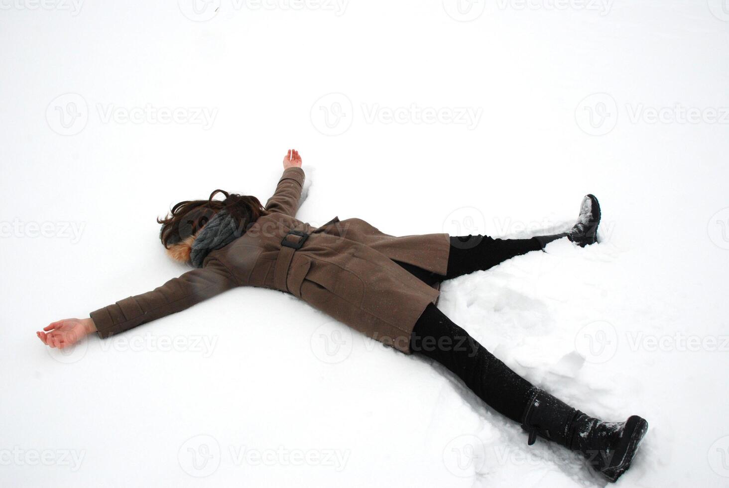 Winter relaxation with woman making snow angel outdoors in nature photo