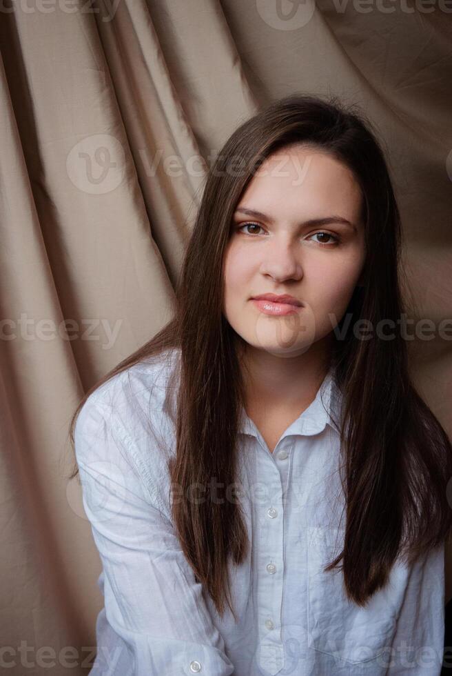 Portrait of a young woman with long hair in a natural setting. Caucasian woman with glitter on face. Beige background photo