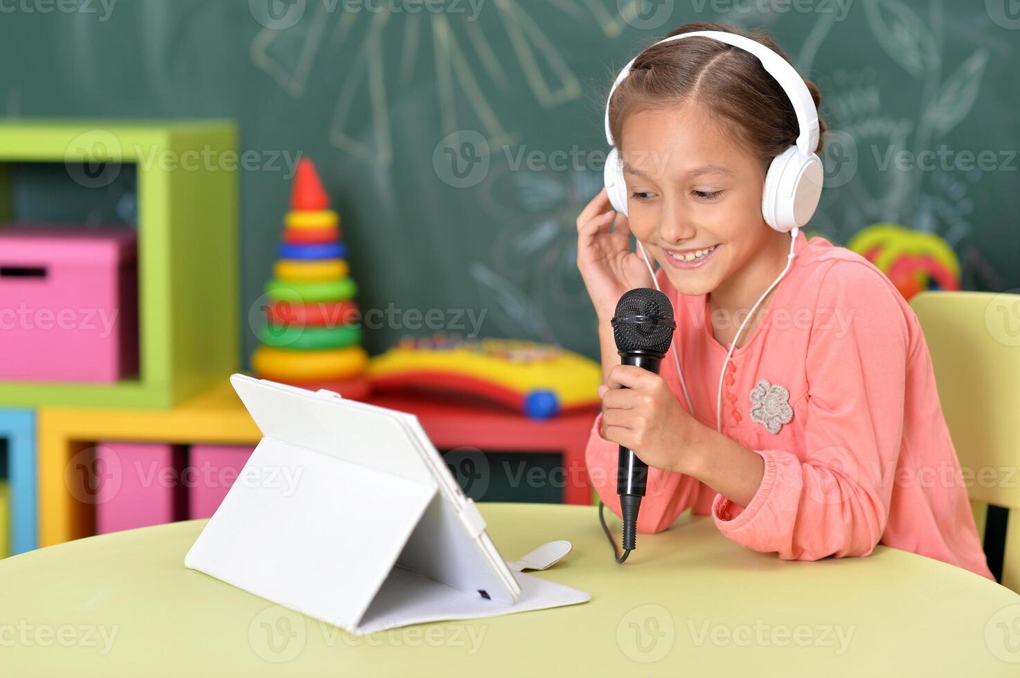 Happy little girl singing karaoke at home photo