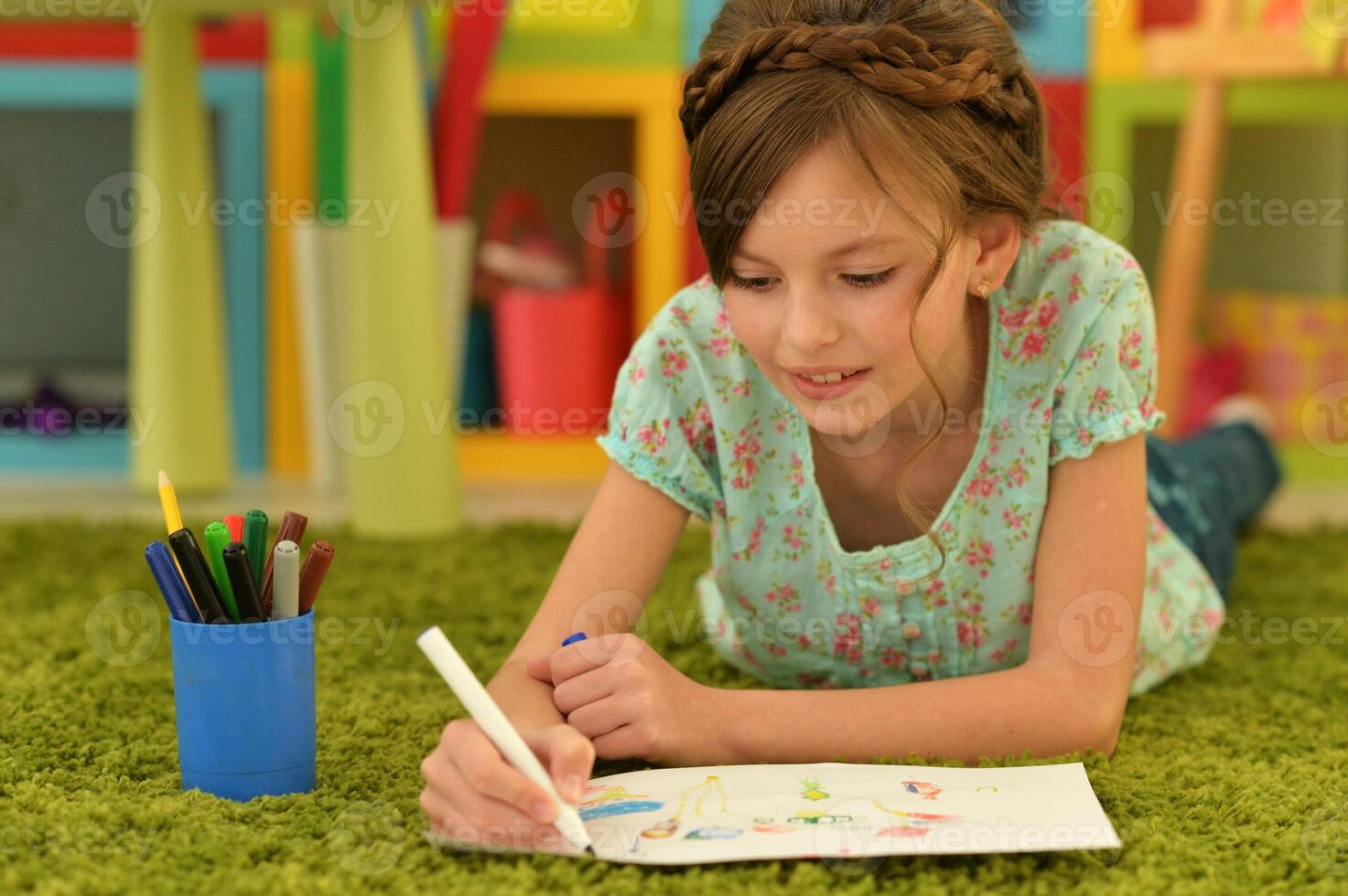 girl in the nursery draws lying on the carpet. photo