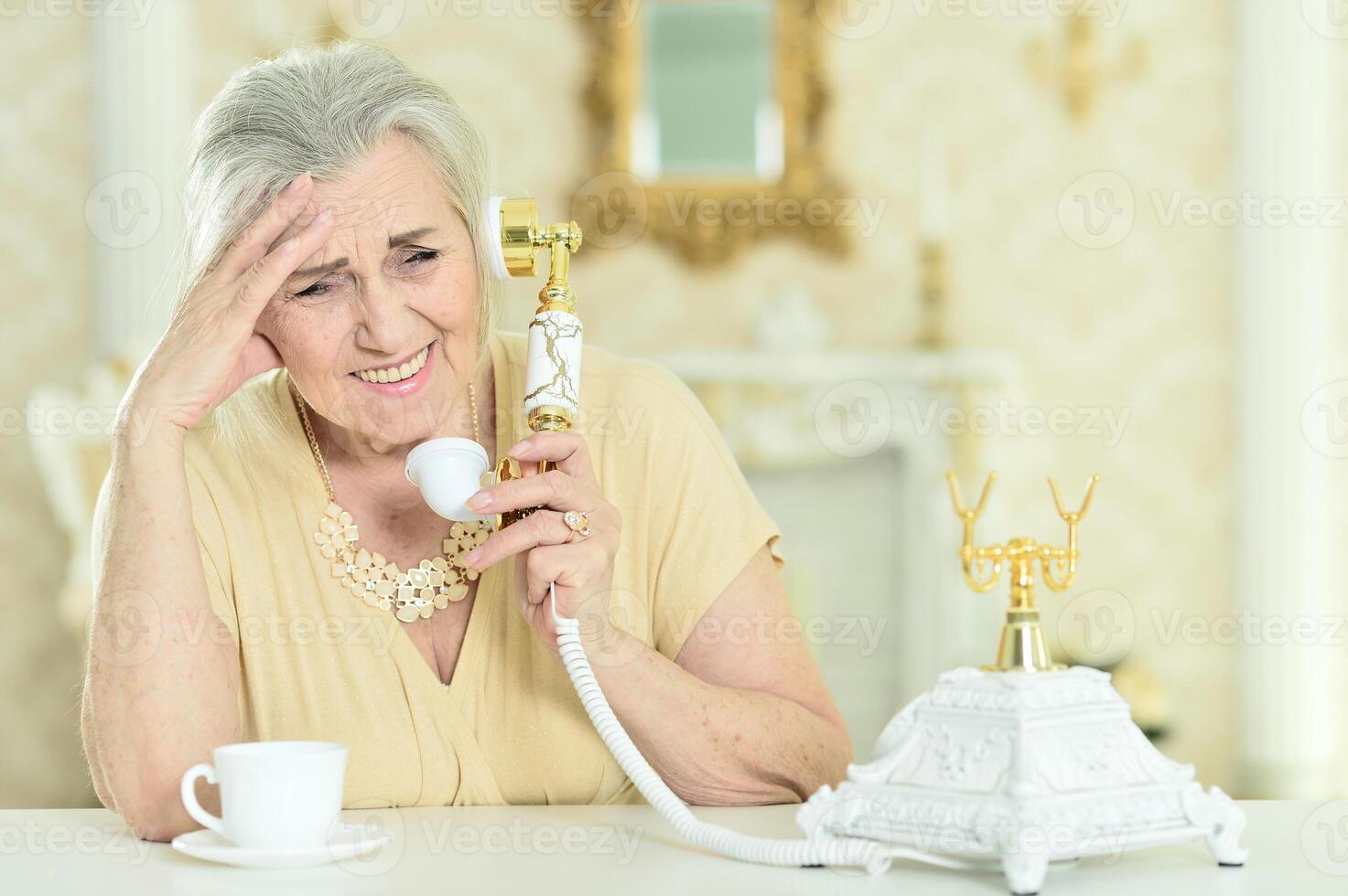 Beautiful elderly woman talking on the phone at home photo