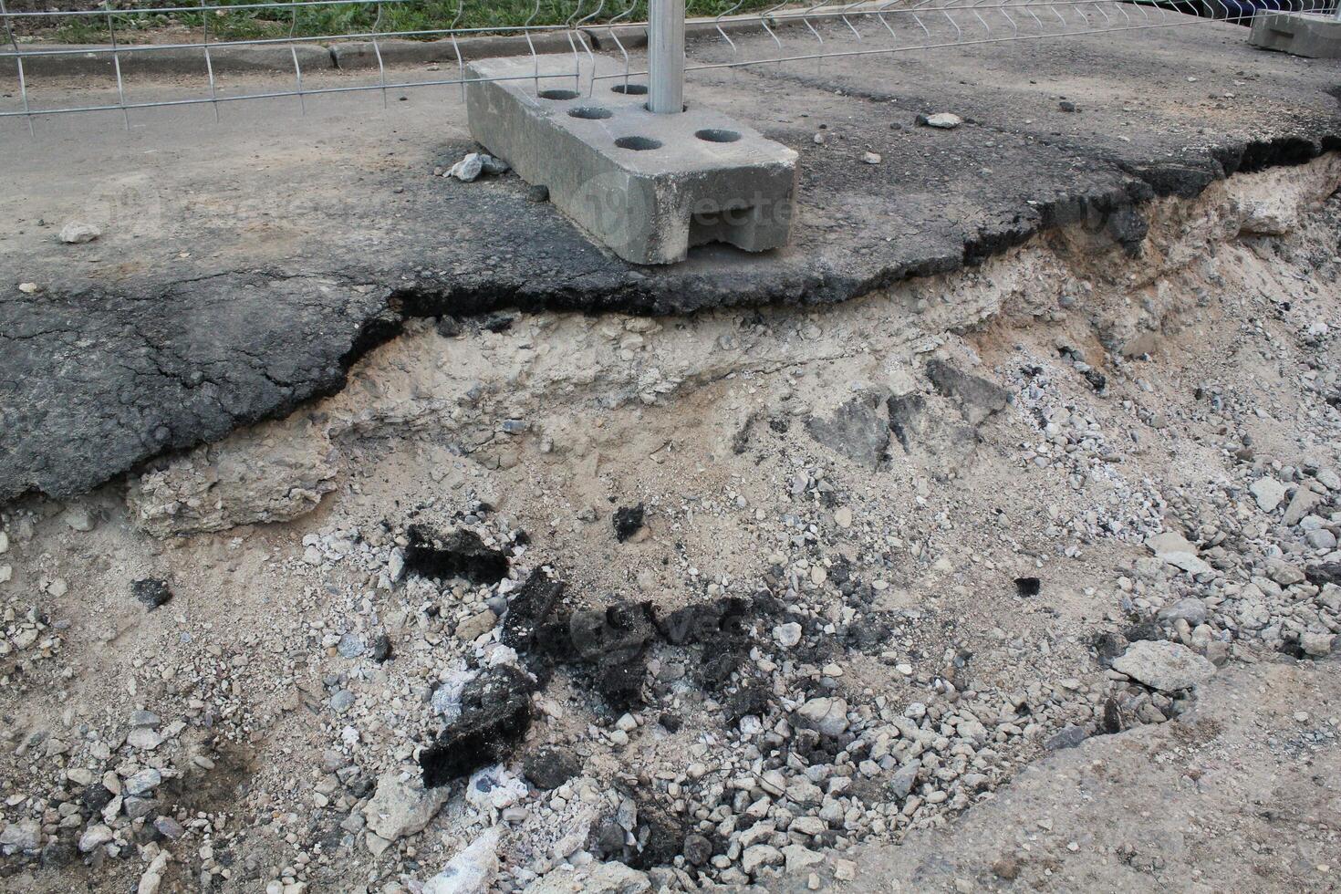 Close-up of a pothole in an asphalt road, damage and deterioration. Rough texture and edges of pothole, need for road repair and maintenance. Concept of infrastructure, transportation or urban decay photo