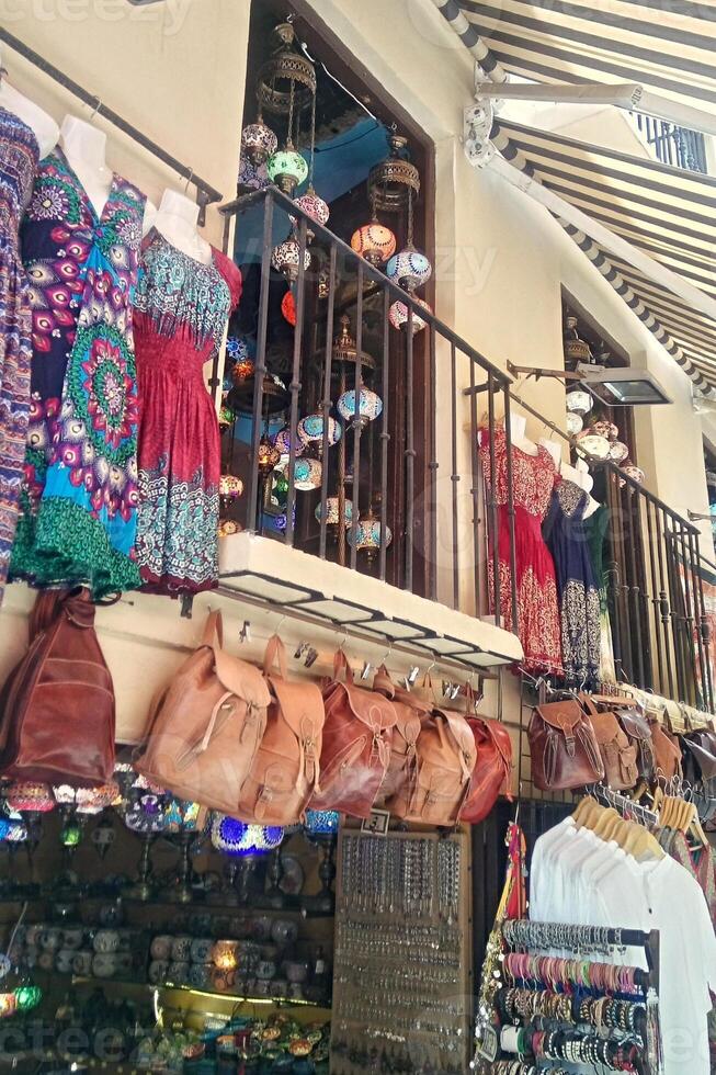 Colorful market stall with dresses, bags, and souvenirs for sale. Tourist destination shopping with vibrant textiles and handcrafted goods photo