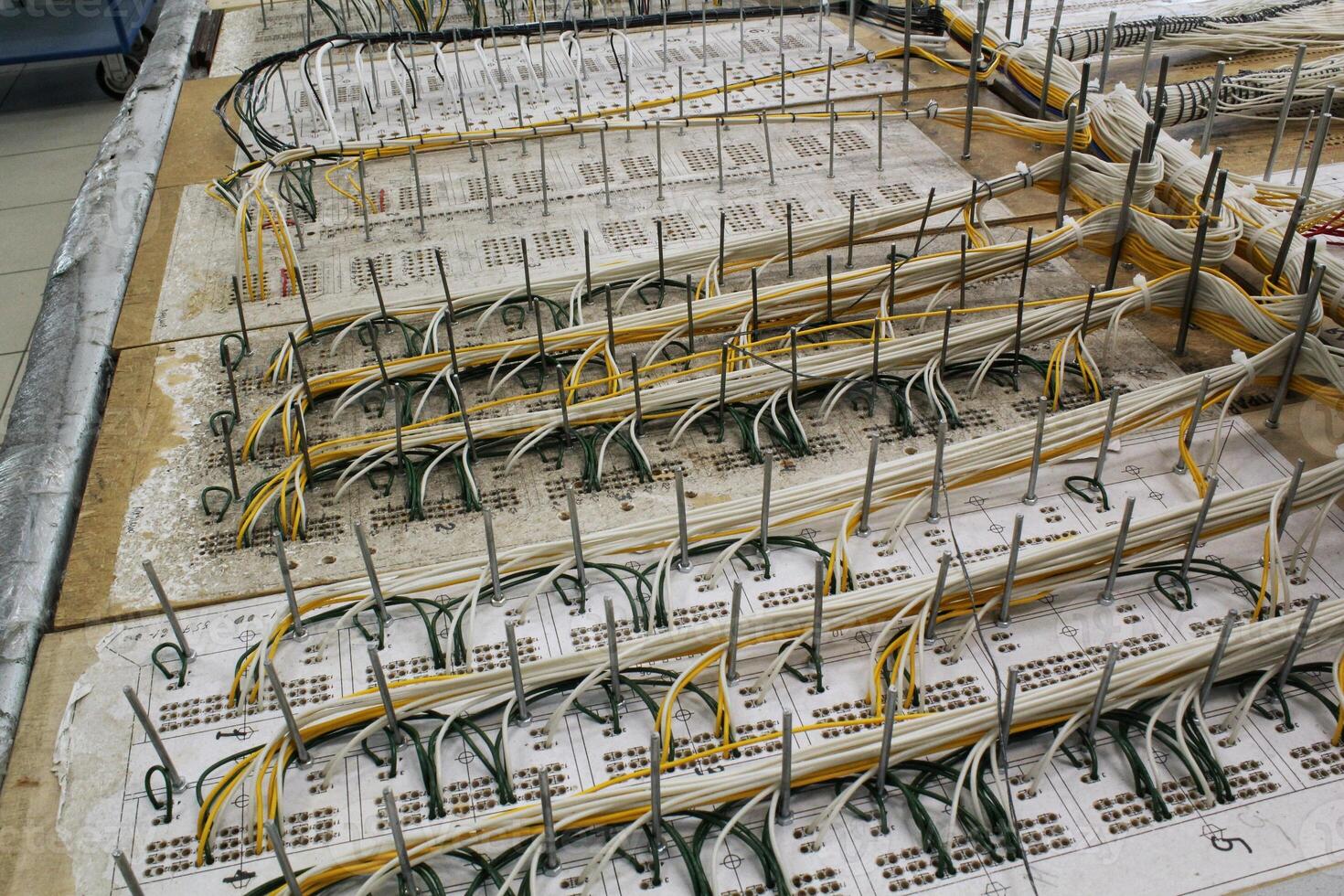 Detailed arrangement of wires and circuits with electrical configuration in workshop. Intricate layout on a workbench in a factory. Organization and complexity of electrical connections photo