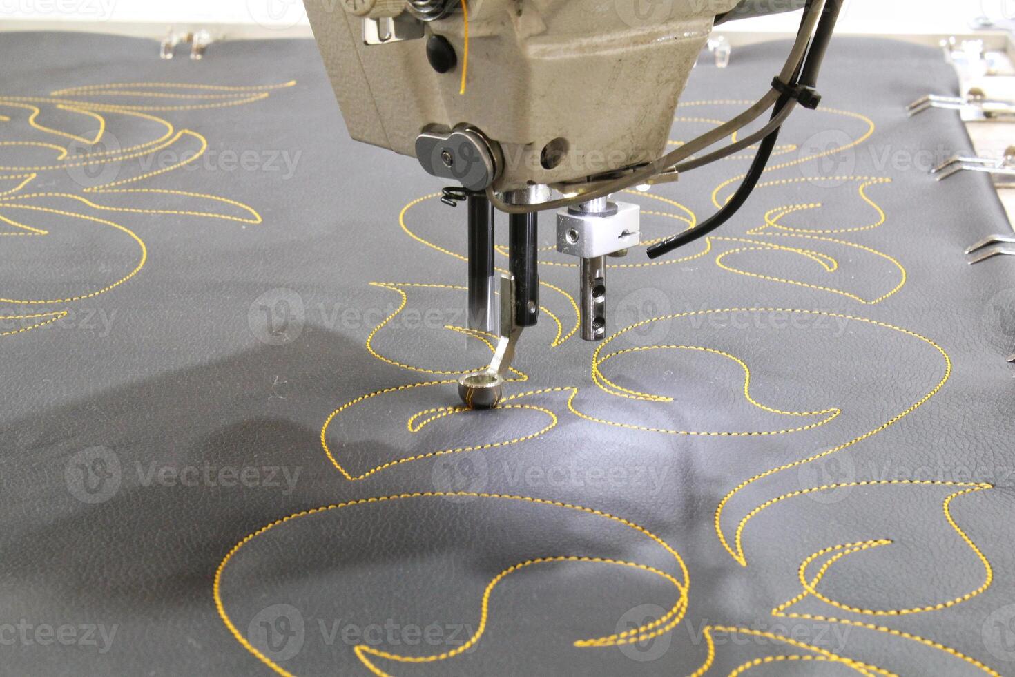 Sewing machine needle in action, stitching yellow thread on gray fabric. Close-up view of the needle and thread, showcasing the precision and detail of sewing photo