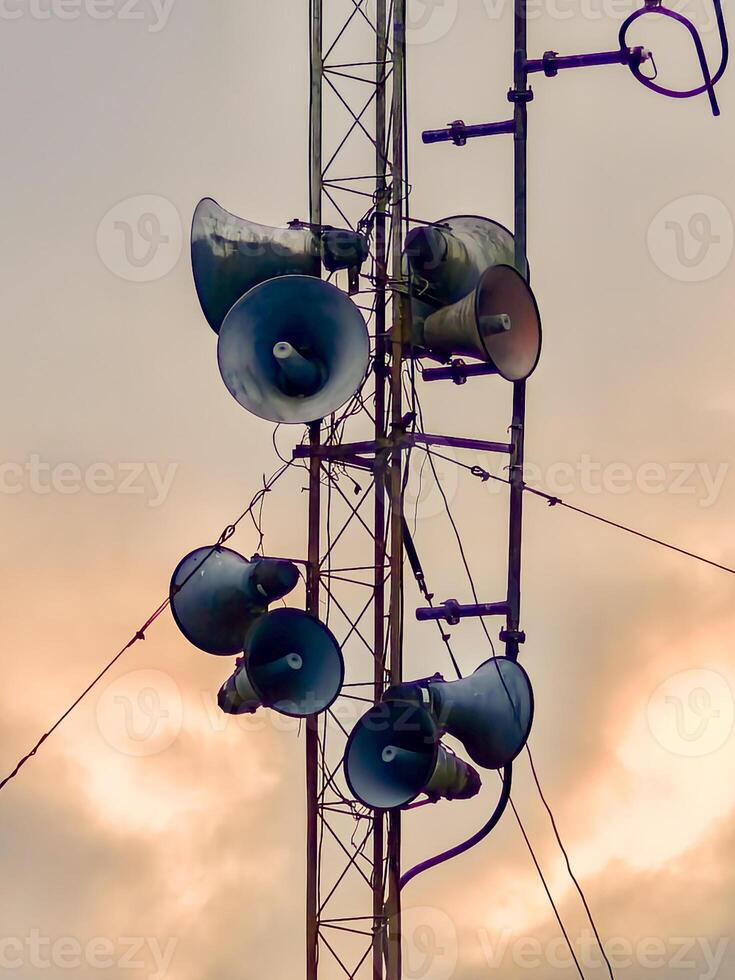 Vintage Communication Tower with Multiple Loudspeakers Against a Dramatic Sky at Sunset photo