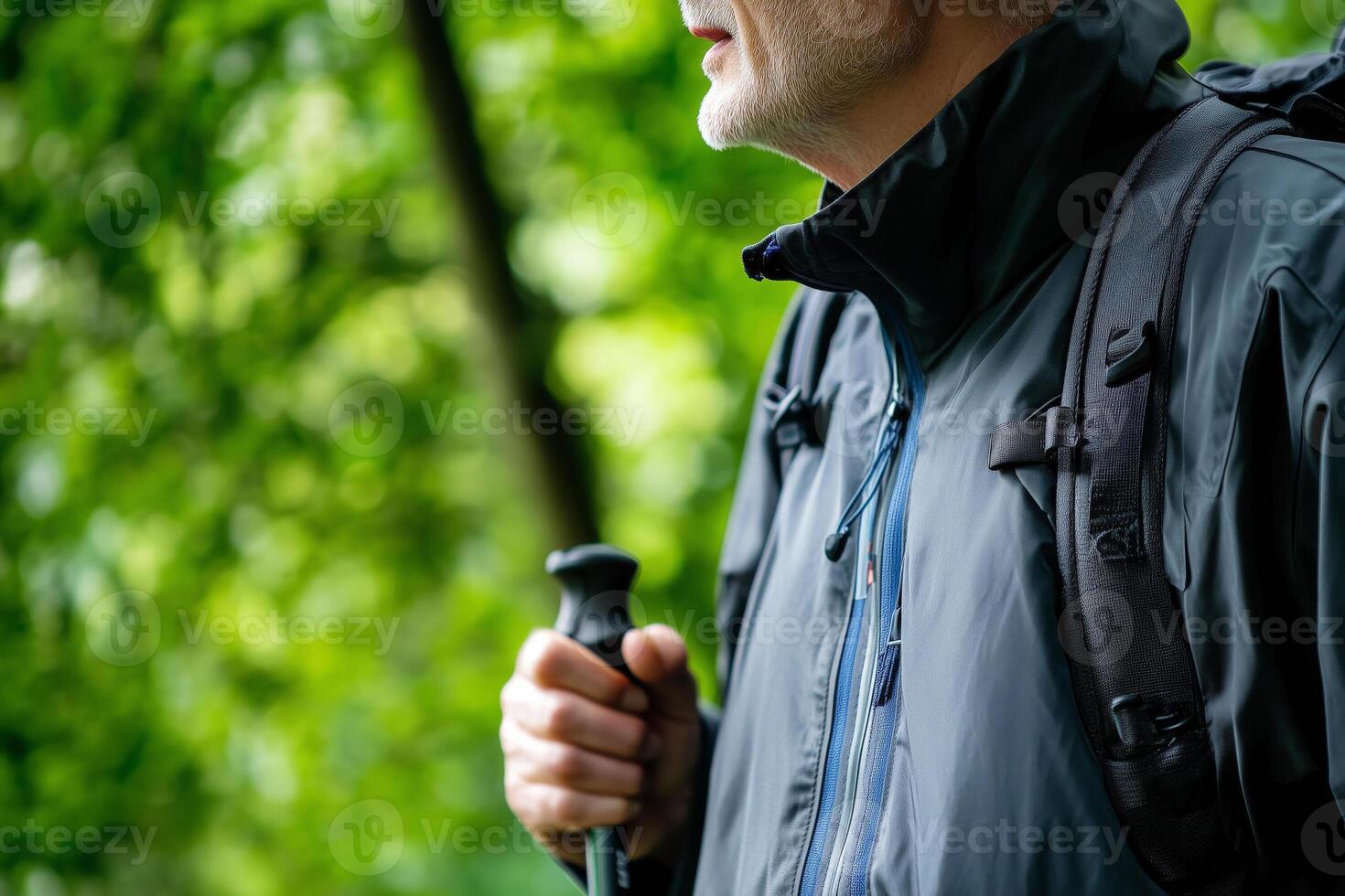 Close up of a senior man with hiking poles walking in the forest photo
