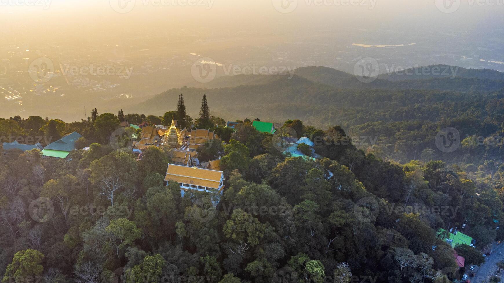 Wat Phra That Doi Suthep temple shining on forested mountain at sunset over Chiang Mai photo