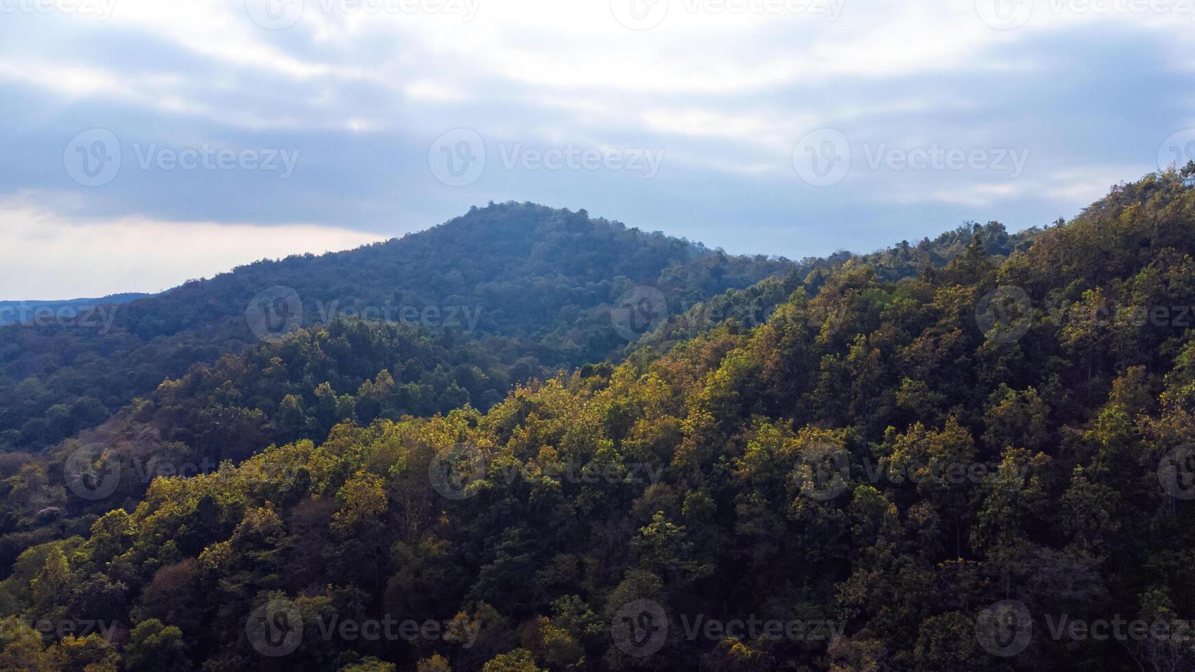 Majestic mountain range in Chiang Mai covered by lush forest under cloudy sky photo