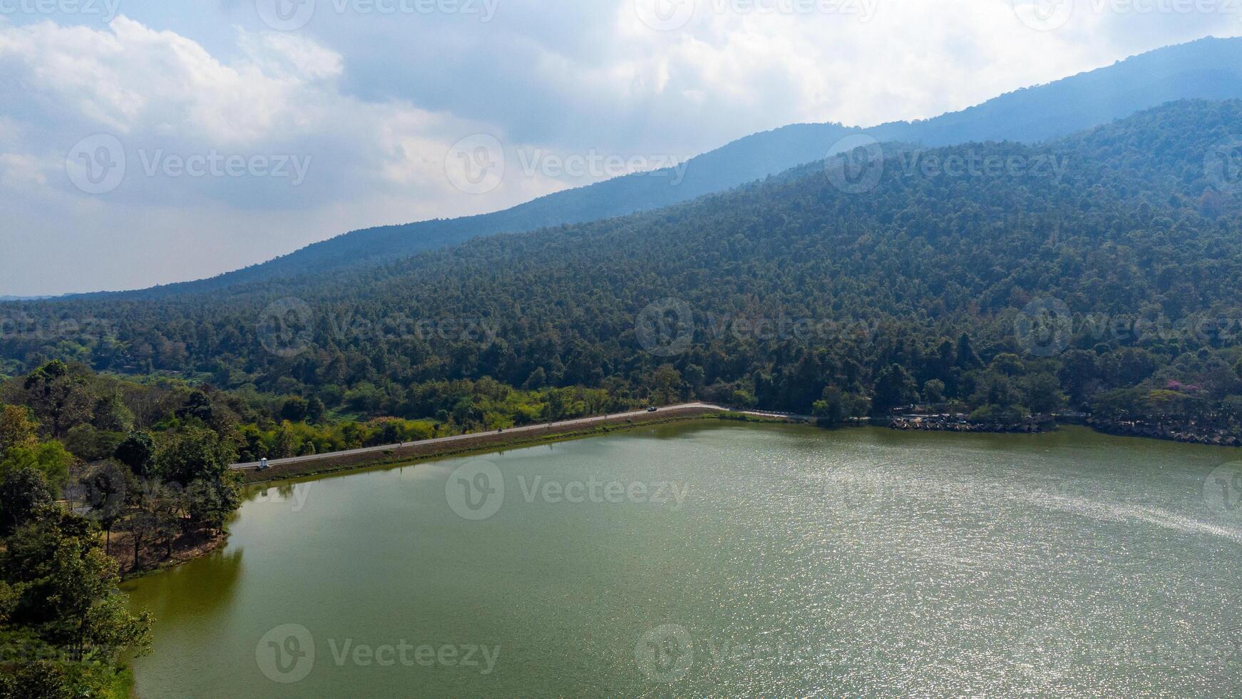 Aerial view of Huay Tueng Thao Reservoir with mountain and forest background reflecting sunlight in Thailand photo
