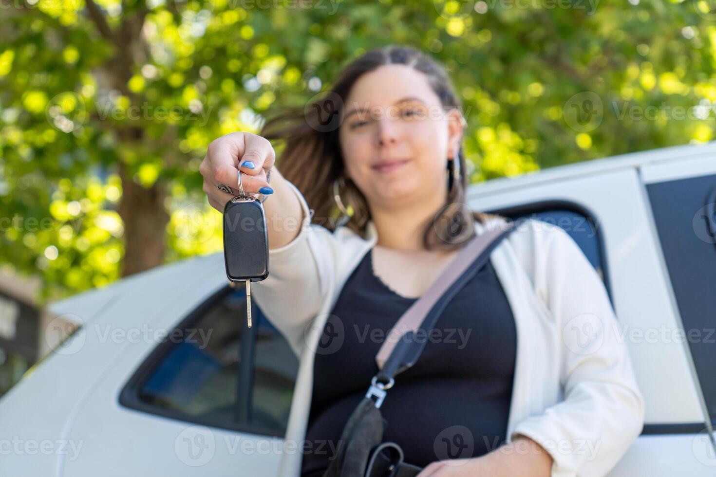 Young woman holding car keys in front of her new car photo