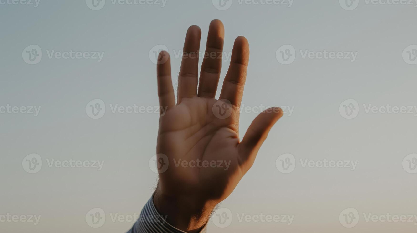 Hand raised against a sunset background showcasing human expression and connection. photo