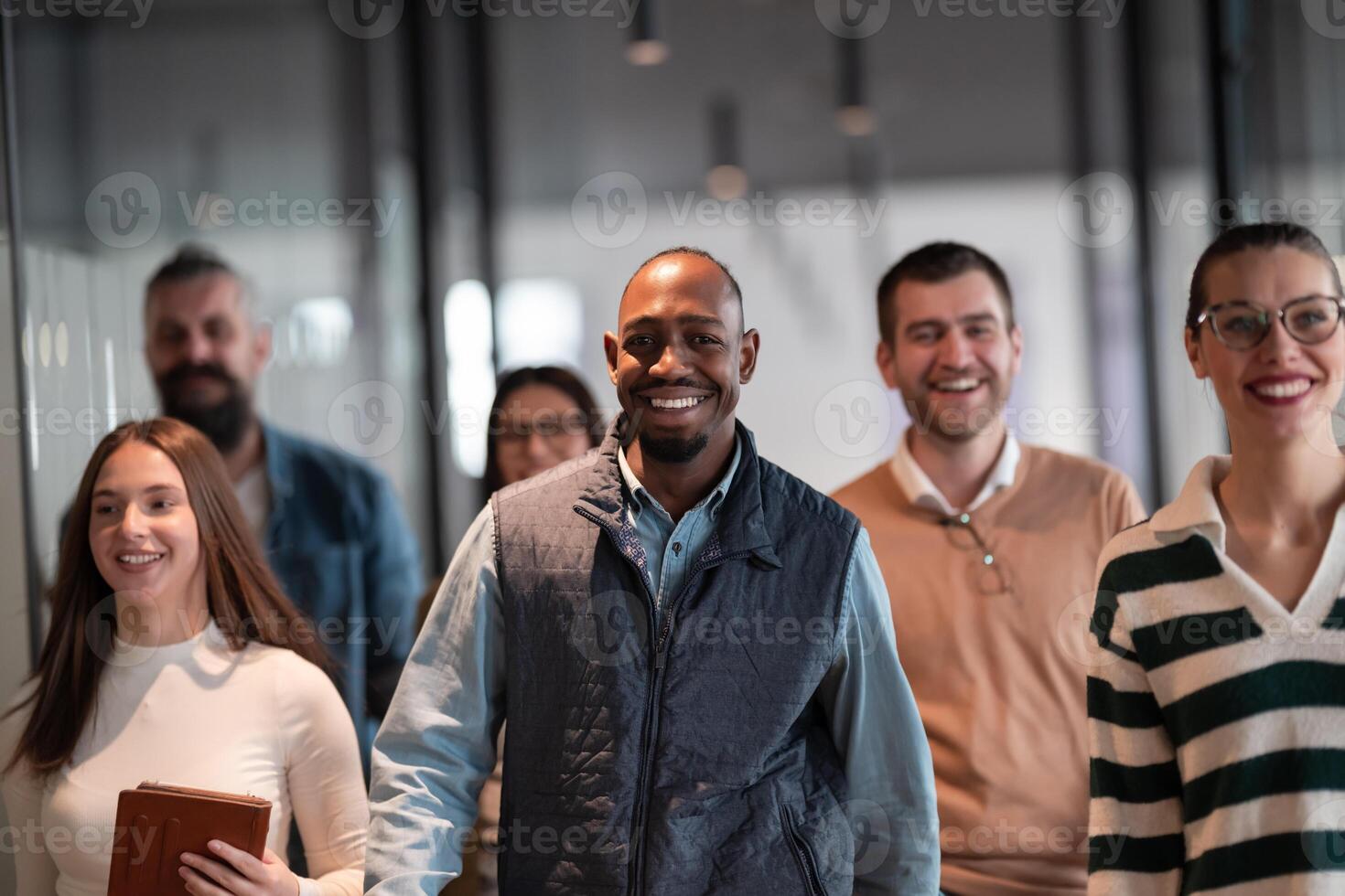 Business team in a modern open space startup office walking together. Diverse group of businesspeople smiling while having a discussion. Successful mixed race colleagues collaborating on a new project photo