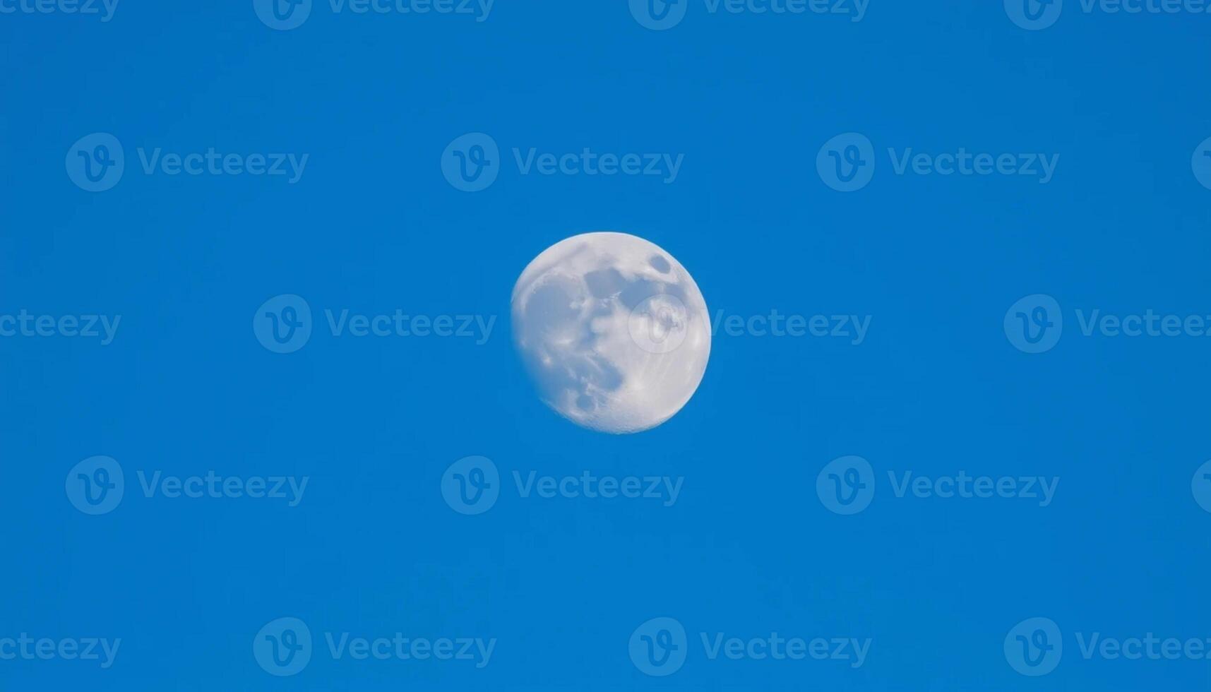The moon is seen in a clear blue sky photo