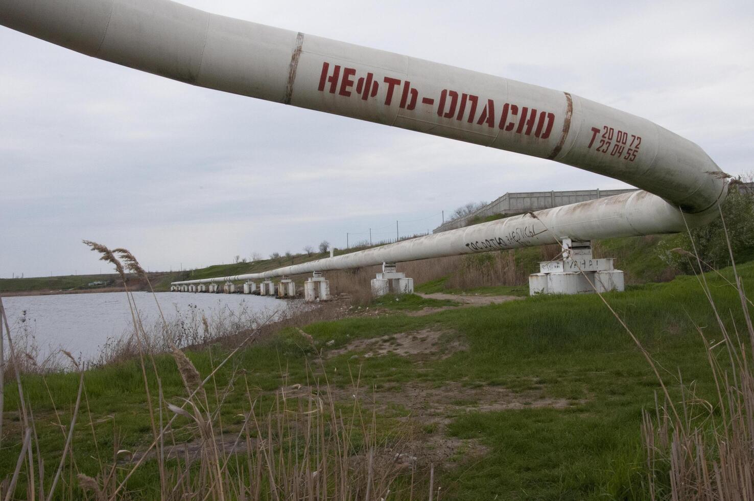 The inscription on the pipe is -oil-dangerous, Ecological problem. Pipe for pumping oil and gas. Ukraine, mart 2017. photo