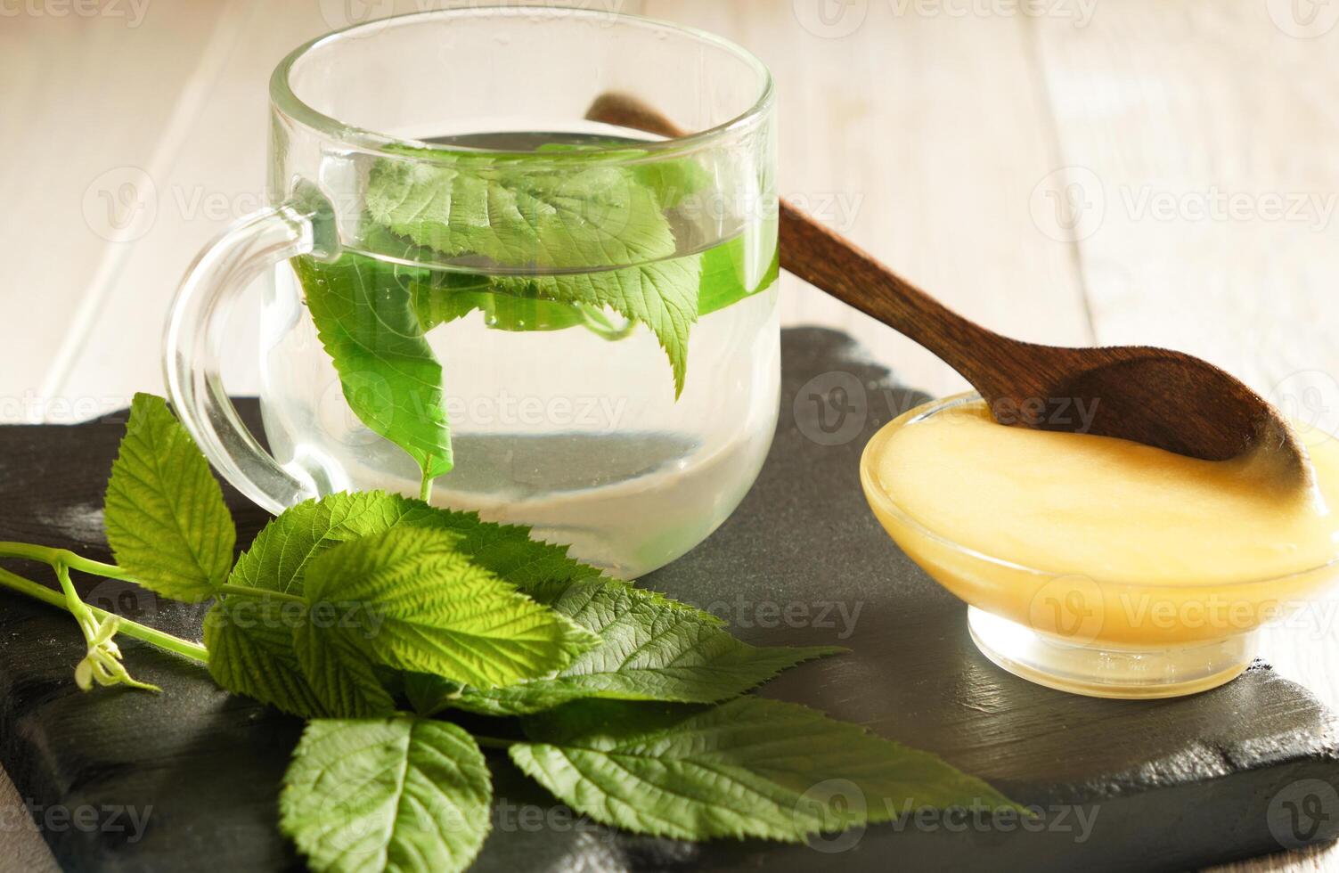 raspberry leaves Tea with Fresh Leaves and Honey on Slate Board photo