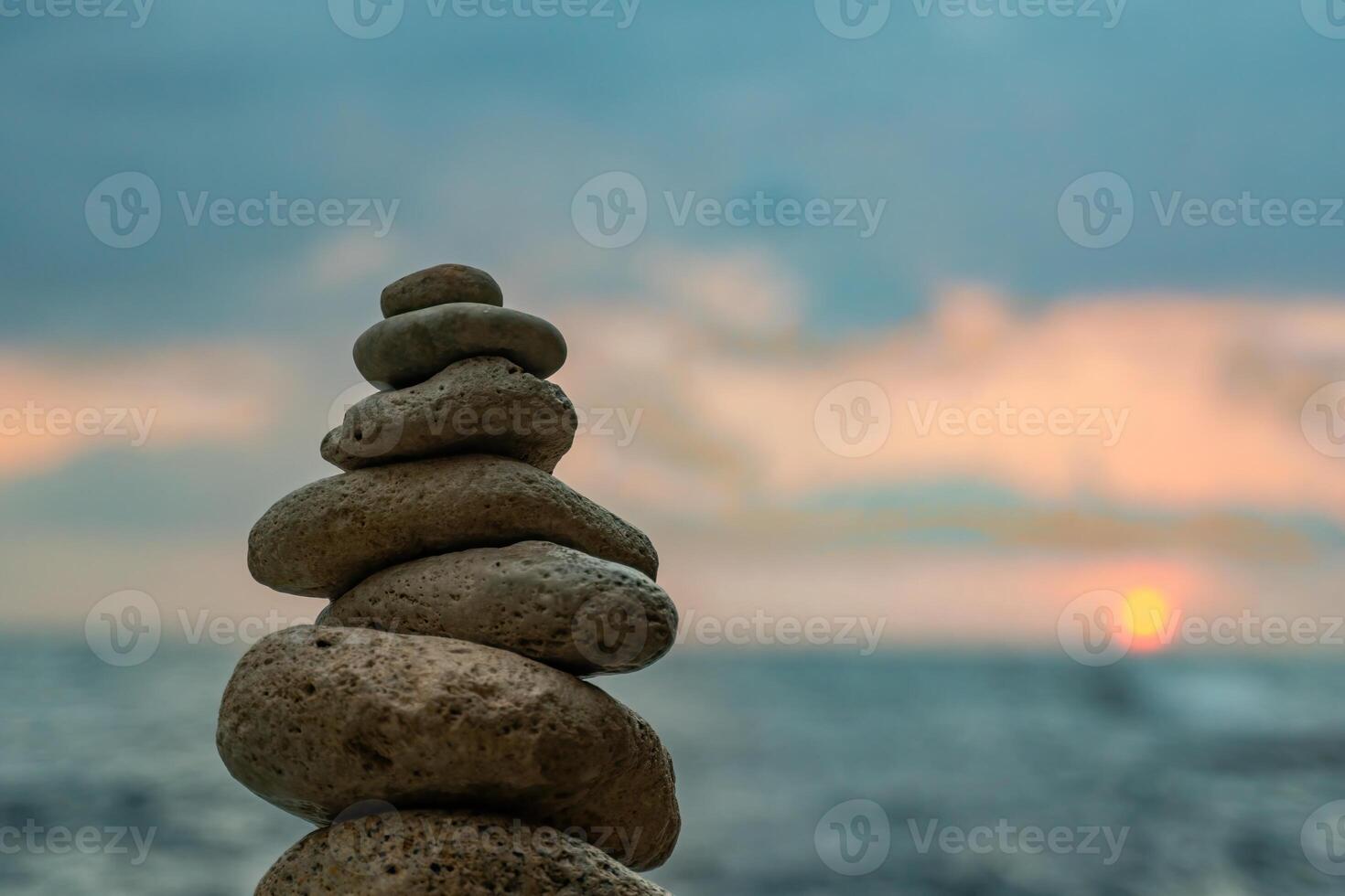 Rocks Stack Sunset Beach - A balanced stack of rocks stands against a beautiful sunset over a calm ocean. photo
