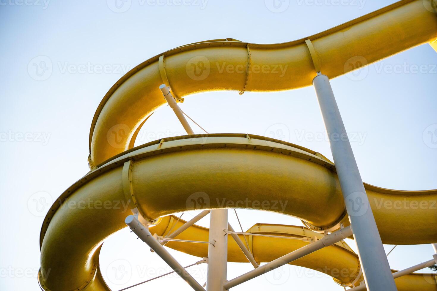 Water Slides Park Summer Fun. Yellow water slides curve against a bright blue sky. photo