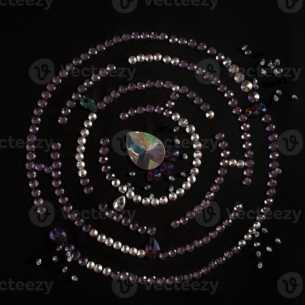 Rhinestones in the form of a labyrinth with a flat lay, isolated on a black background. Top view pattern or labyrinth of rhinestones in lilac and silver color. photo