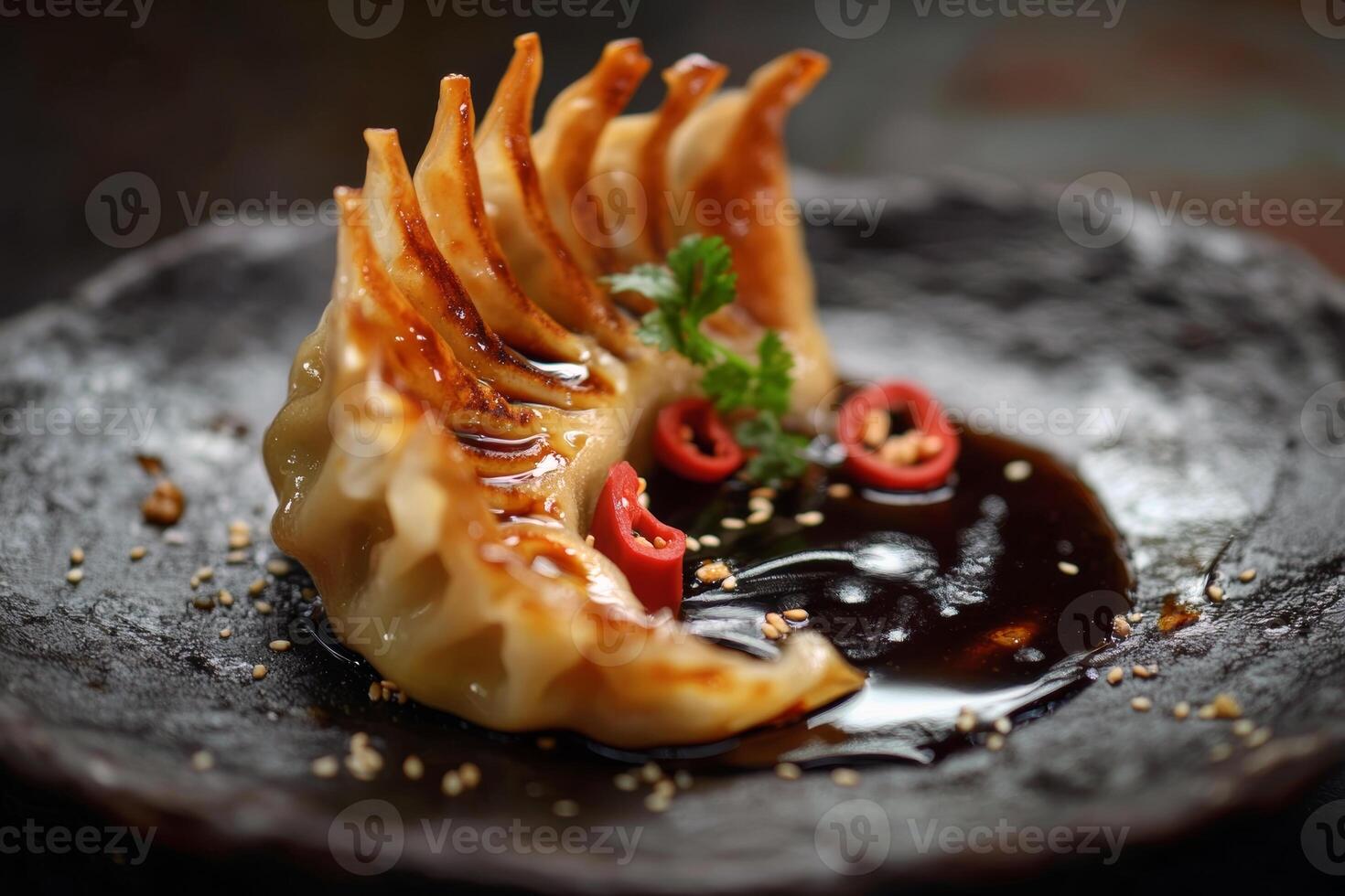 Deliciously grilled dumpling on black plate with soy sauce and garnish photo