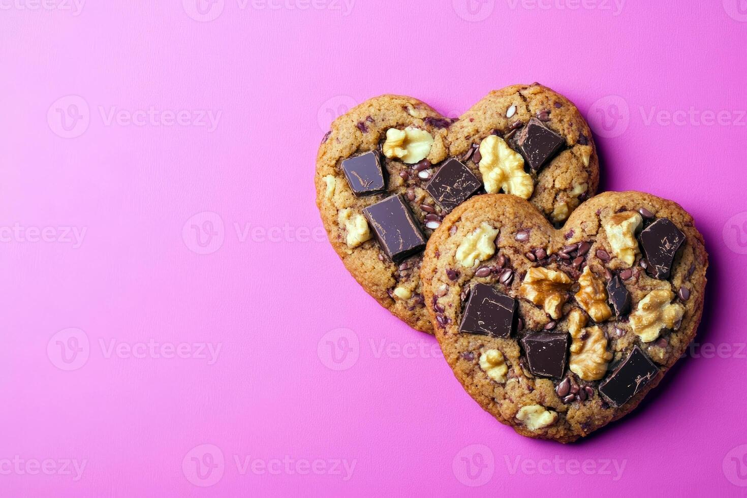 Heart shaped cookies with chocolate chunks and walnuts on pink background photo