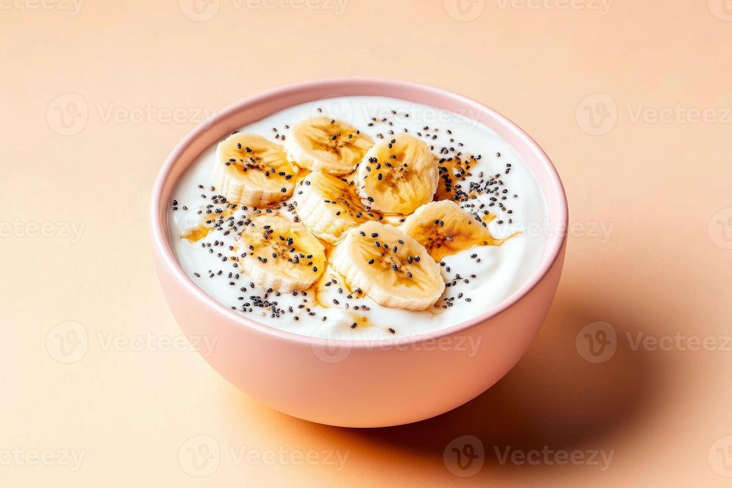 Banana slices and chia seeds on yogurt in a pink bowl against peach background photo