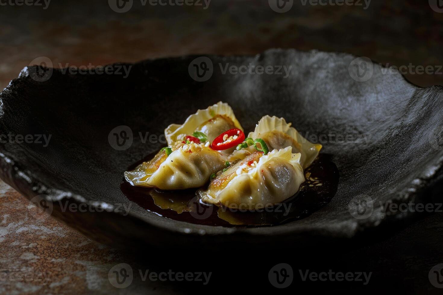 Delicious asian dumplings with soy sauce and red chili in black bowl photo