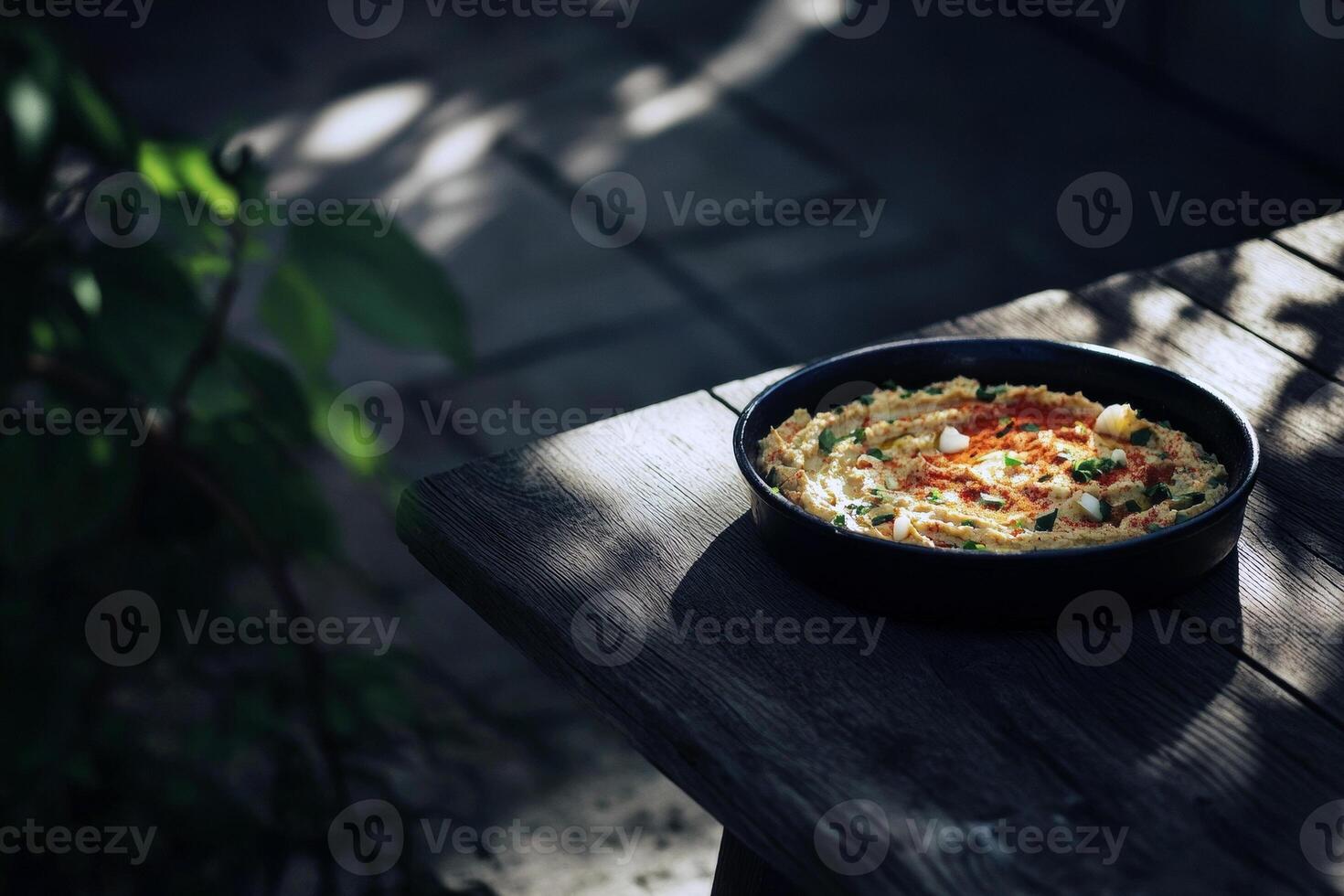 Mediterranean hummus plate on rustic wooden table in sunlit garden photo