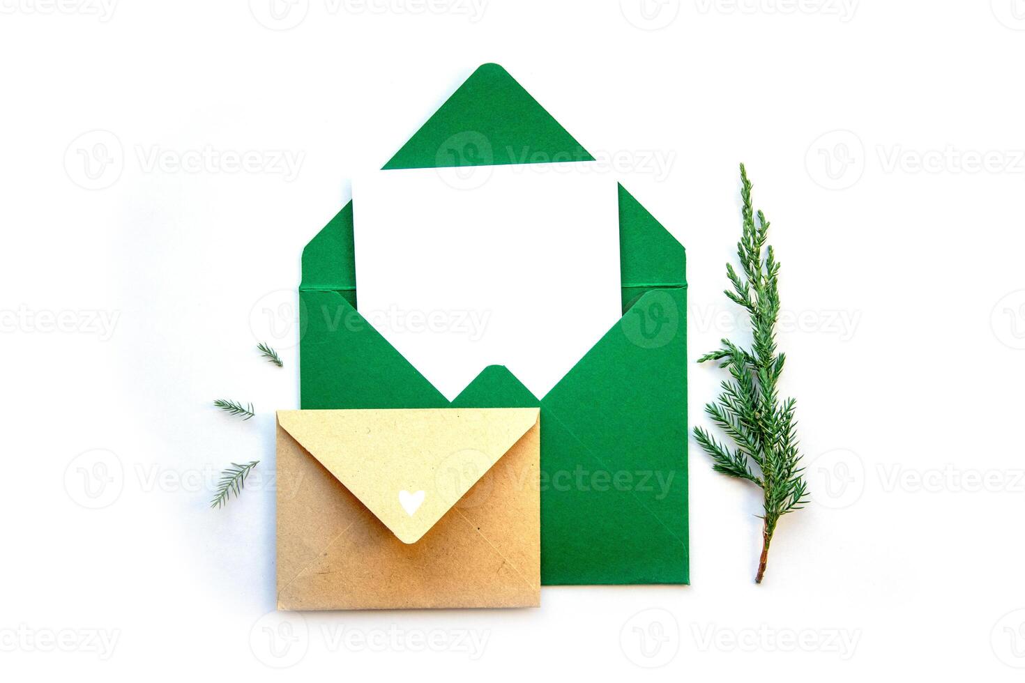 Colorful green envelopes with a blank card and a small brown envelope beside pine sprigs on a white background photo