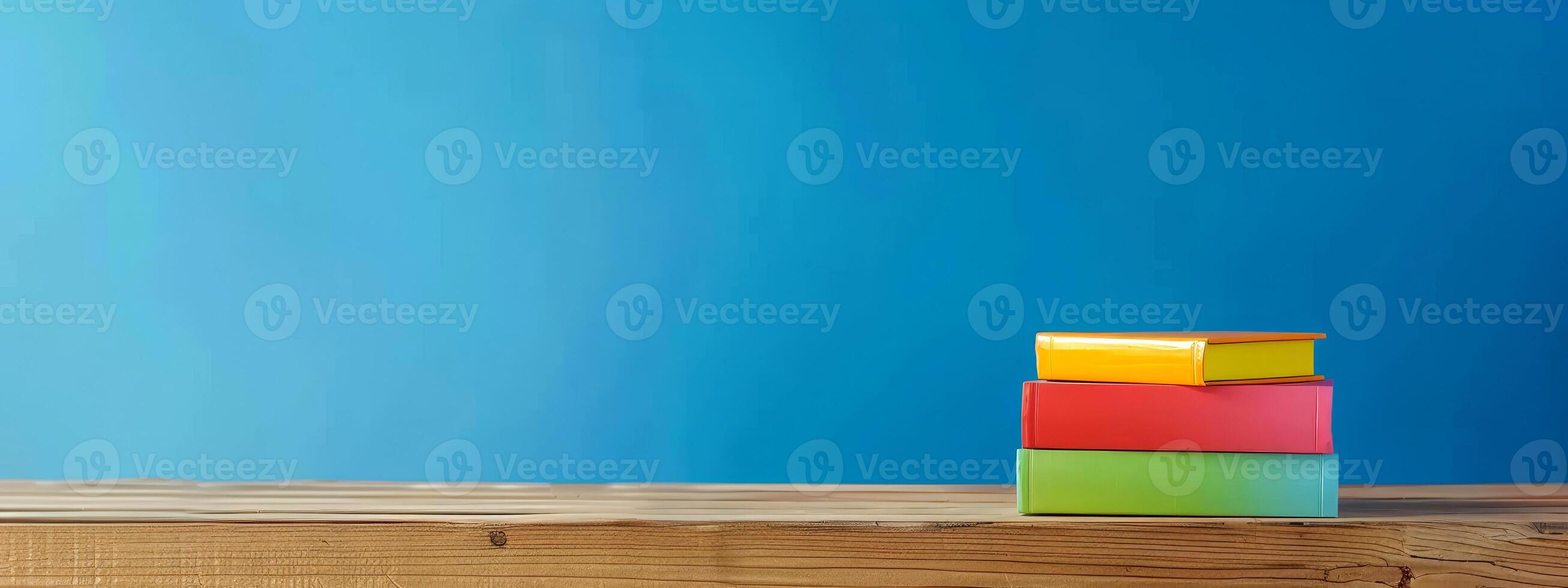 A stack of brightly colored books is arranged neatly on a rustic wooden table, adding vibrancy to the space and inviting a sense of curiosity and creativity photo