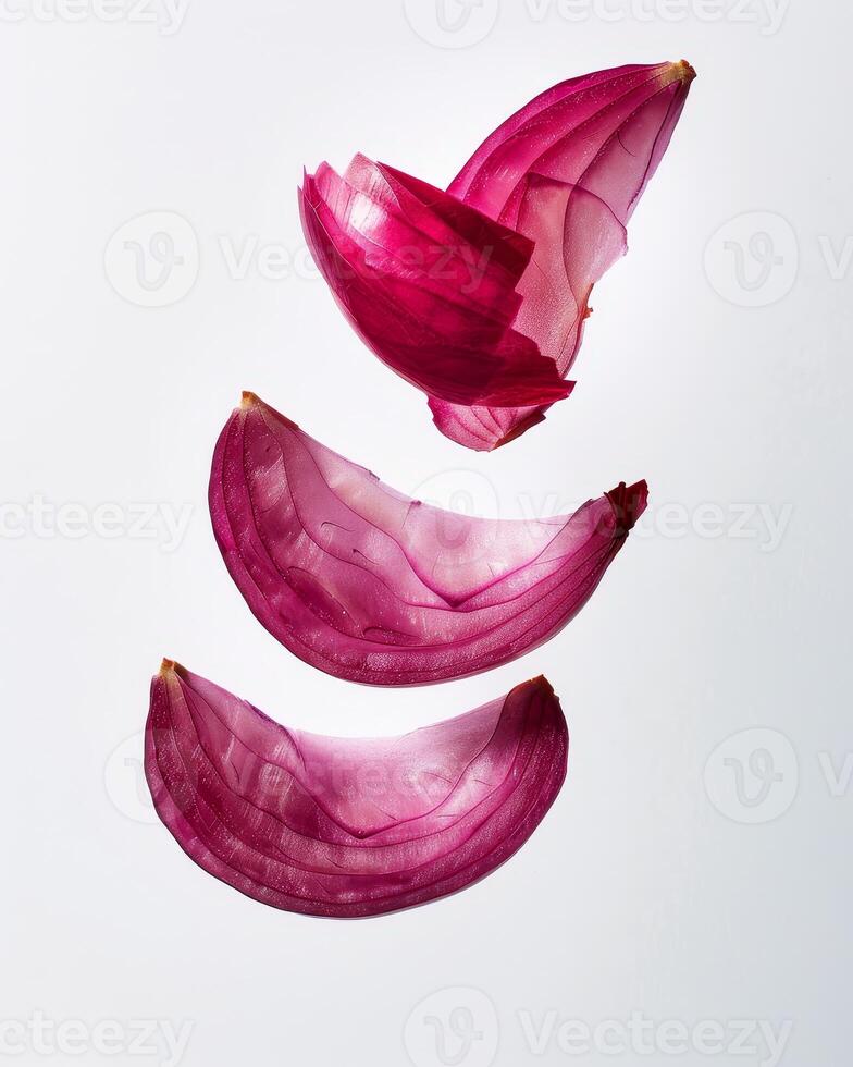 Four pieces of a red onion are suspended in the air, revealing their delicate layers and rich color. This unique display emphasizes their natural texture and appeal photo