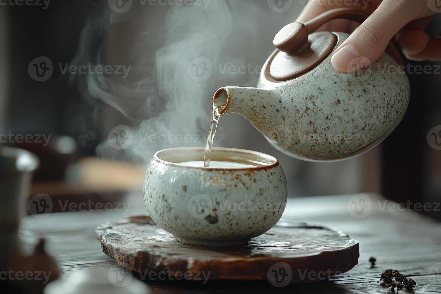 Pouring hot tea from teapot into cup with steam photo