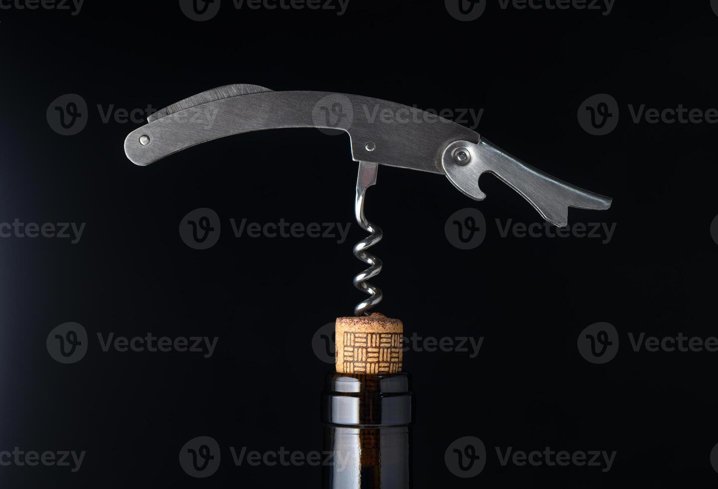 Unique corkscrew elegantly poised above a wine bottle in a stylishly lit environment photo