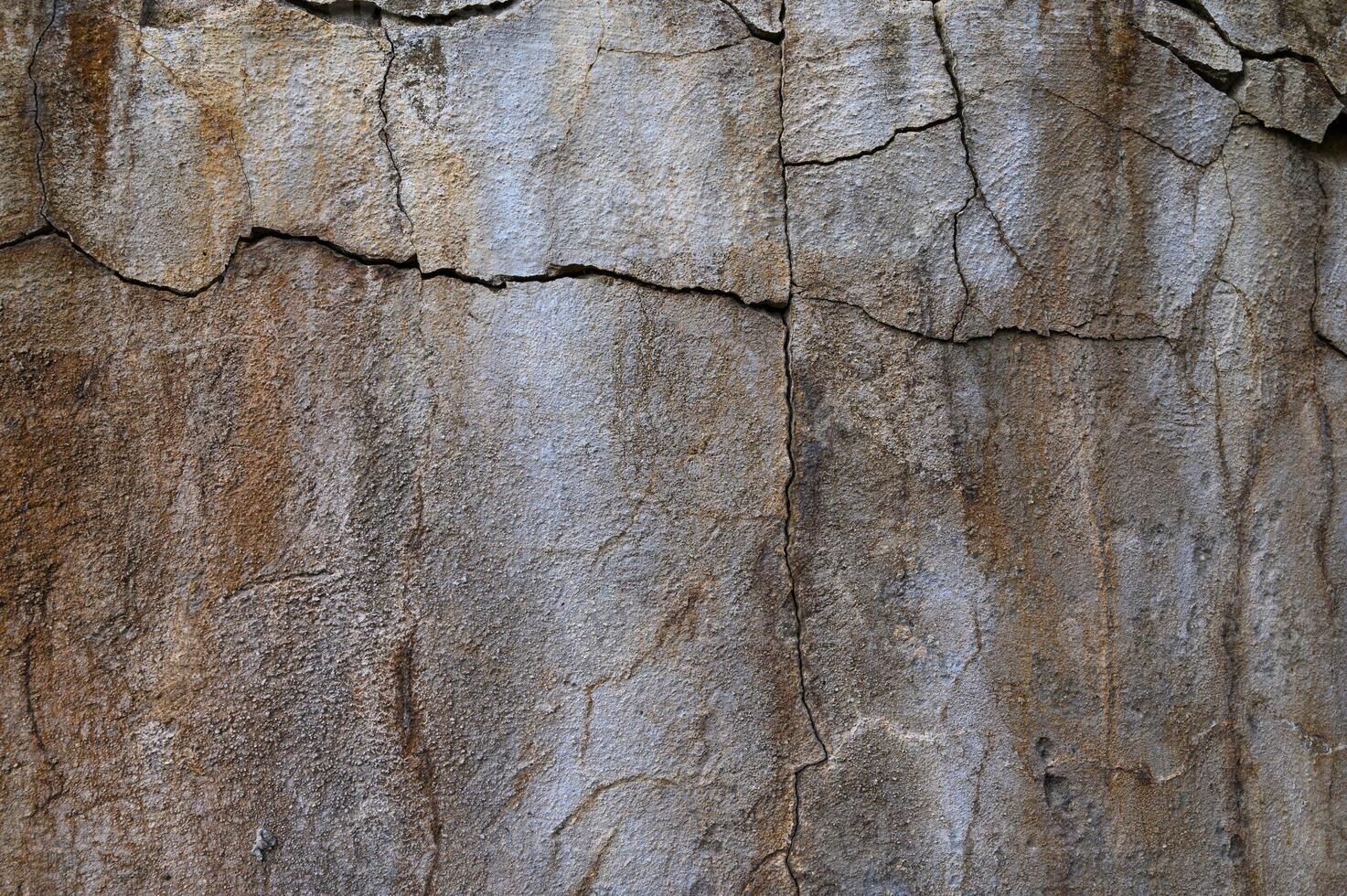 Textured stone wall displaying natural patterns and earthy tones in a rustic outdoor setting photo