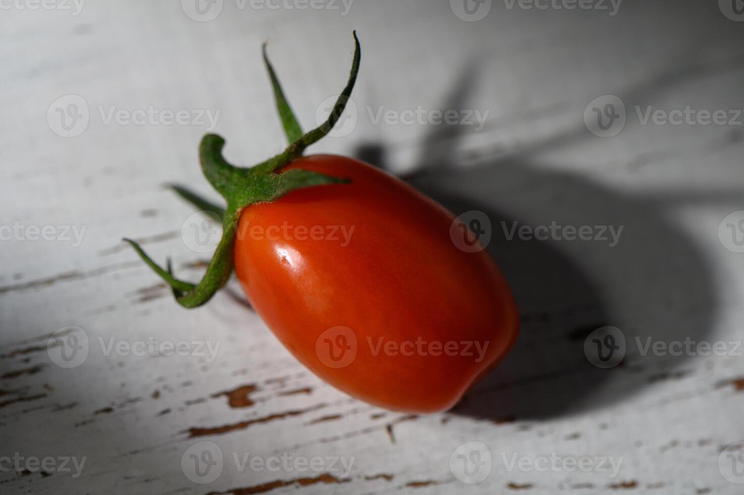 Freshly harvested tomato beautifully resting on a rustic wooden surface basking in soft afternoon light photo
