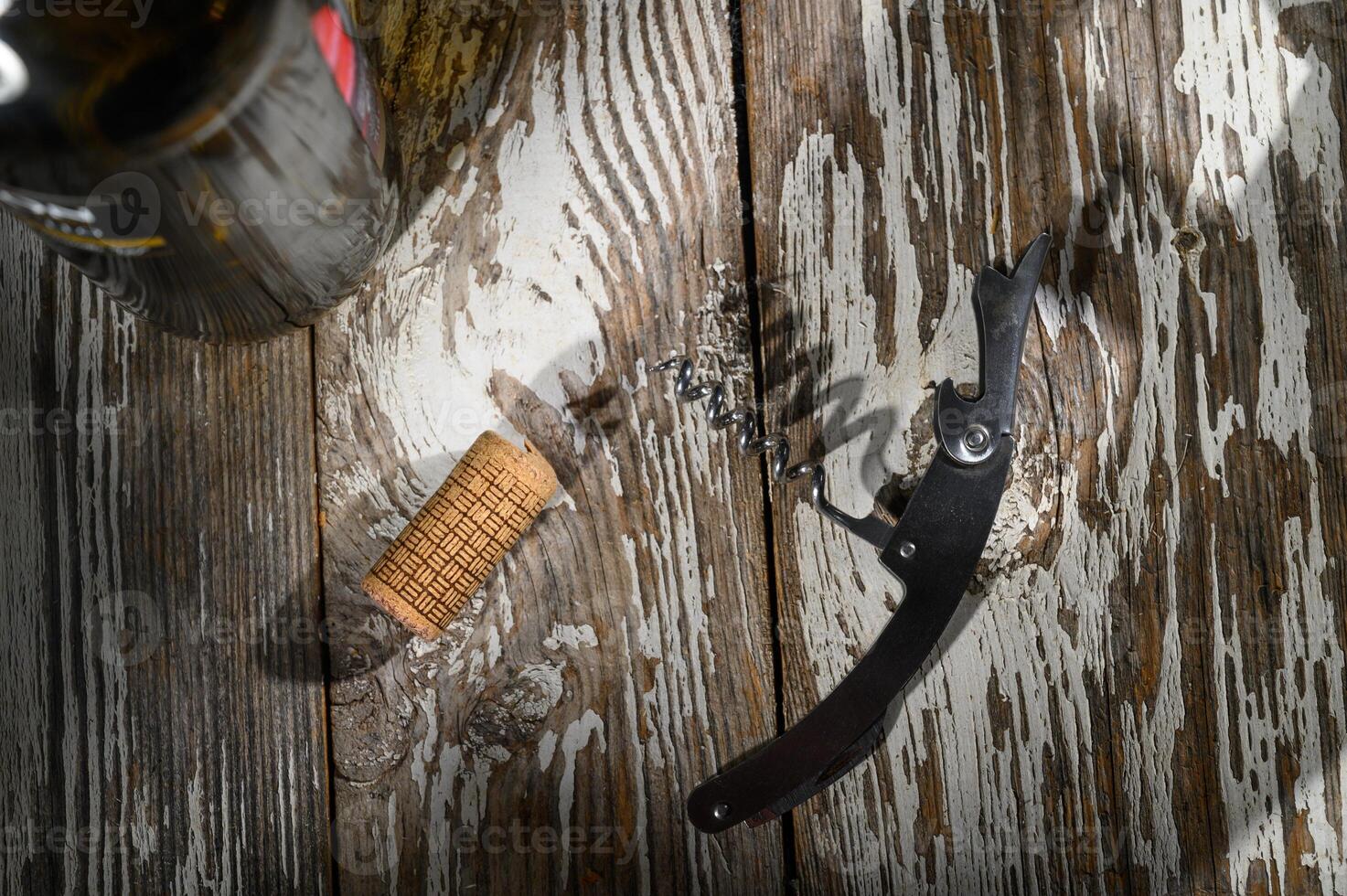 Corkscrew and cork resting on rustic wooden table beside a bottle waiting to be opened photo