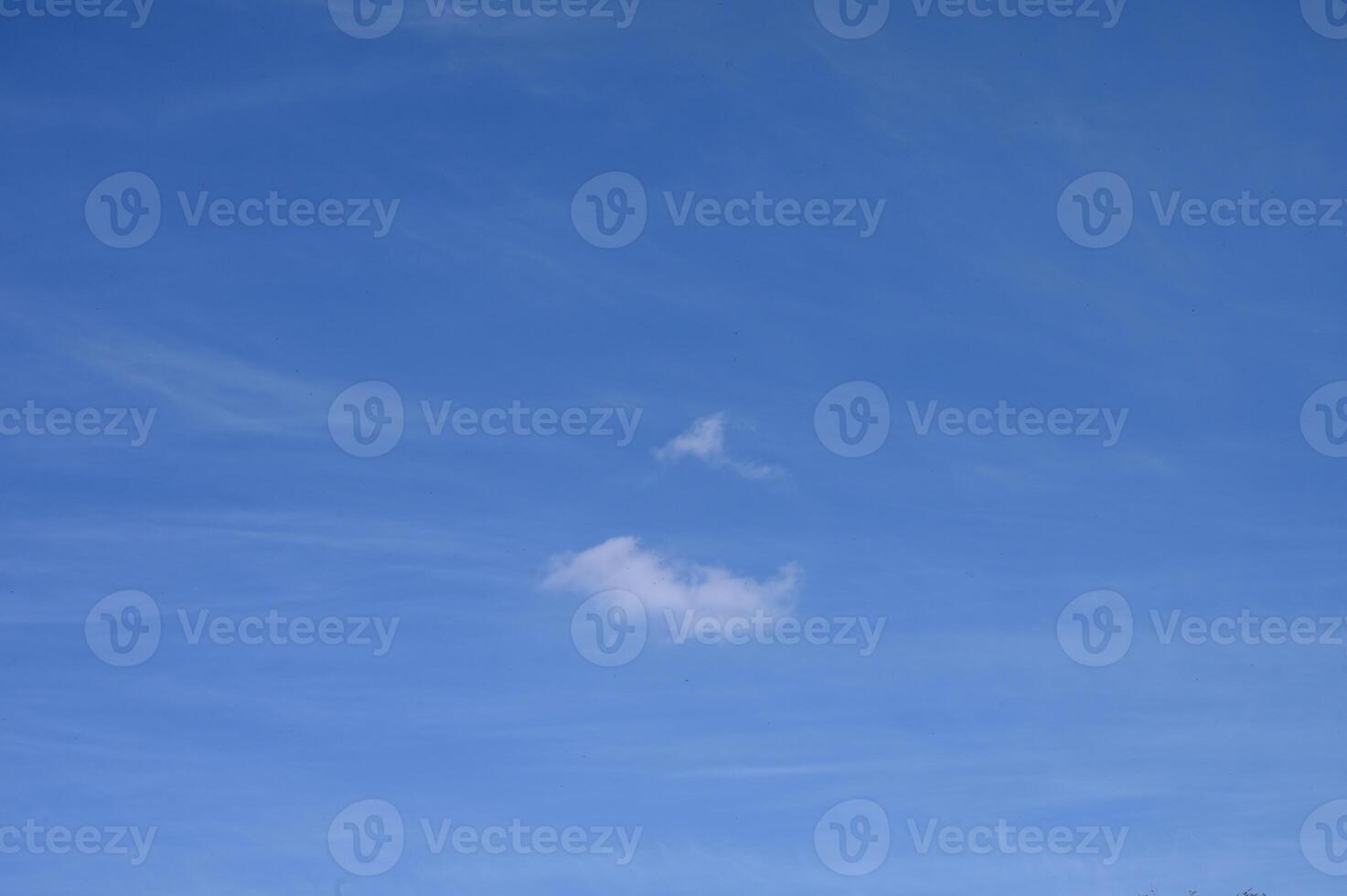 Fluffy cloud shapes drifting in the expansive blue sky during a serene afternoon photo
