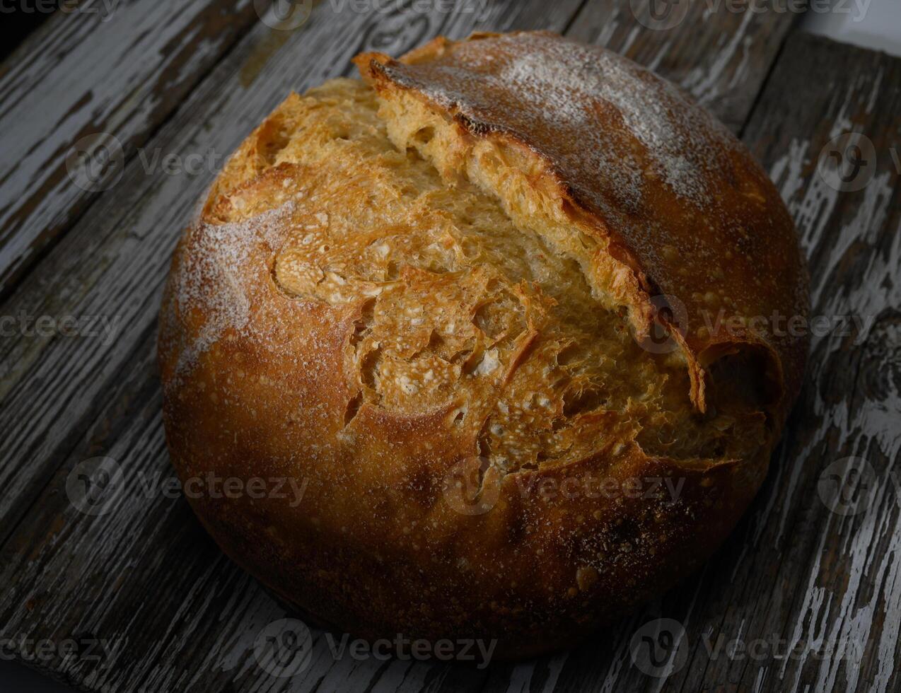 Artisan loaf resting on rustic wooden surface in warm light showcasing its texture and golden crust photo