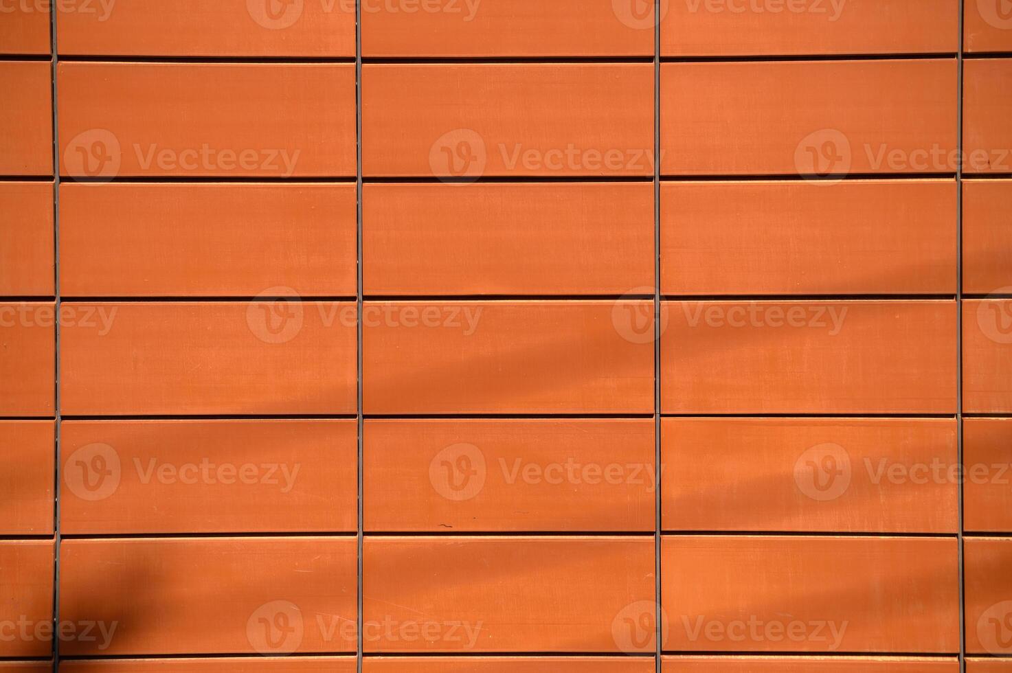 Warm hues of textured clay tiles on a modern building during afternoon sunlight photo